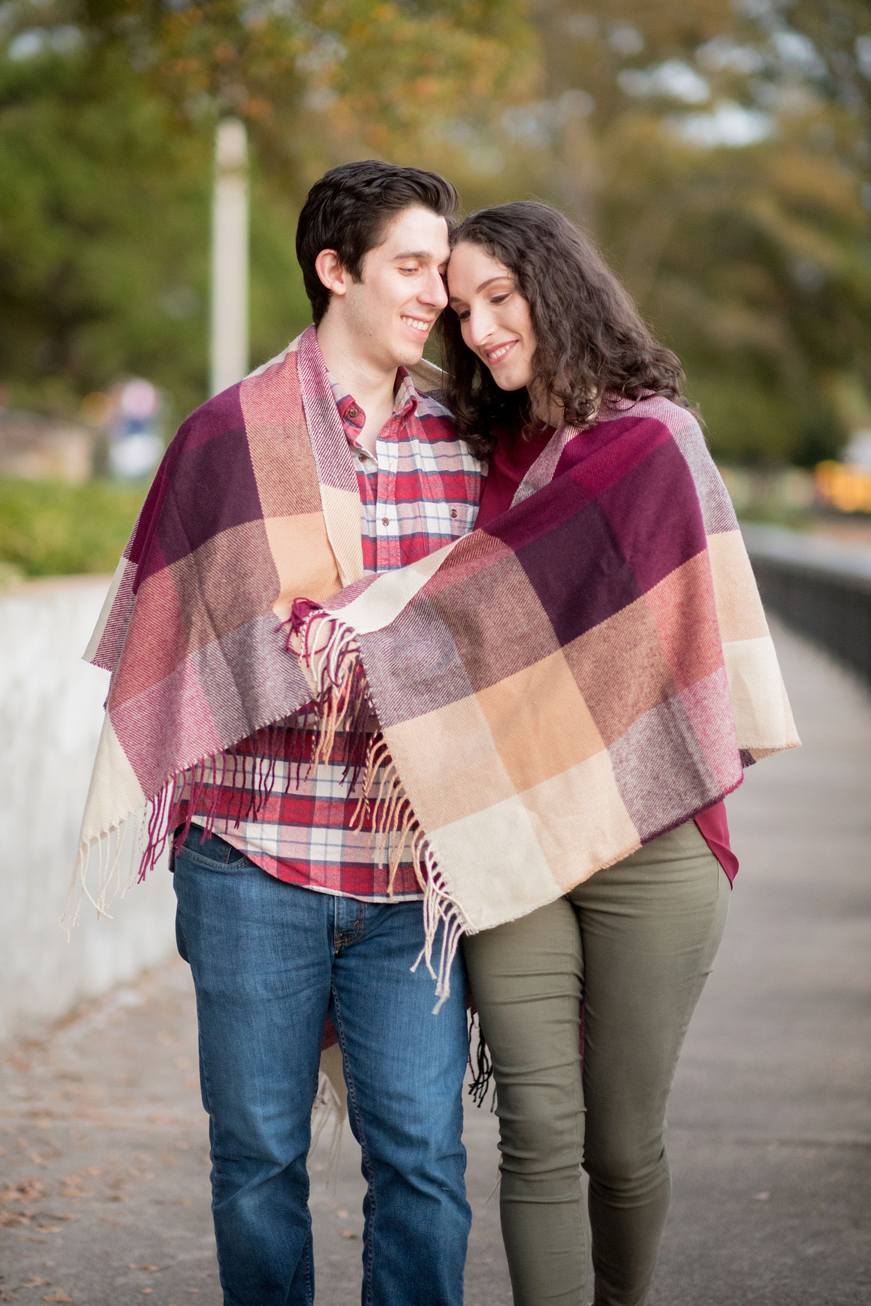 Mikkel Paige Photography photos of a Raleigh engagement session at Pullen Park. The bride and groom got cozy in a burgundy plaid blanket.