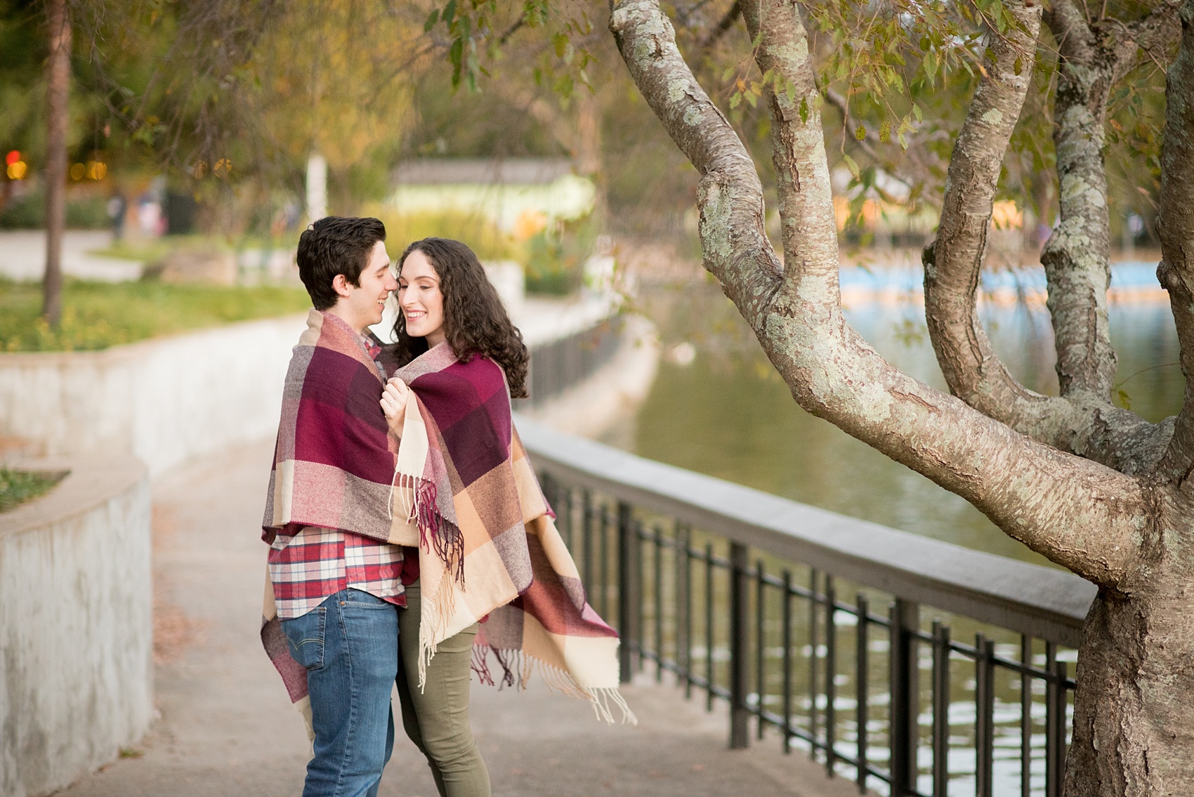 Mikkel Paige Photography photos of a Raleigh engagement session at Pullen Park. The bride and groom got cozy in a burgundy plaid blanket.