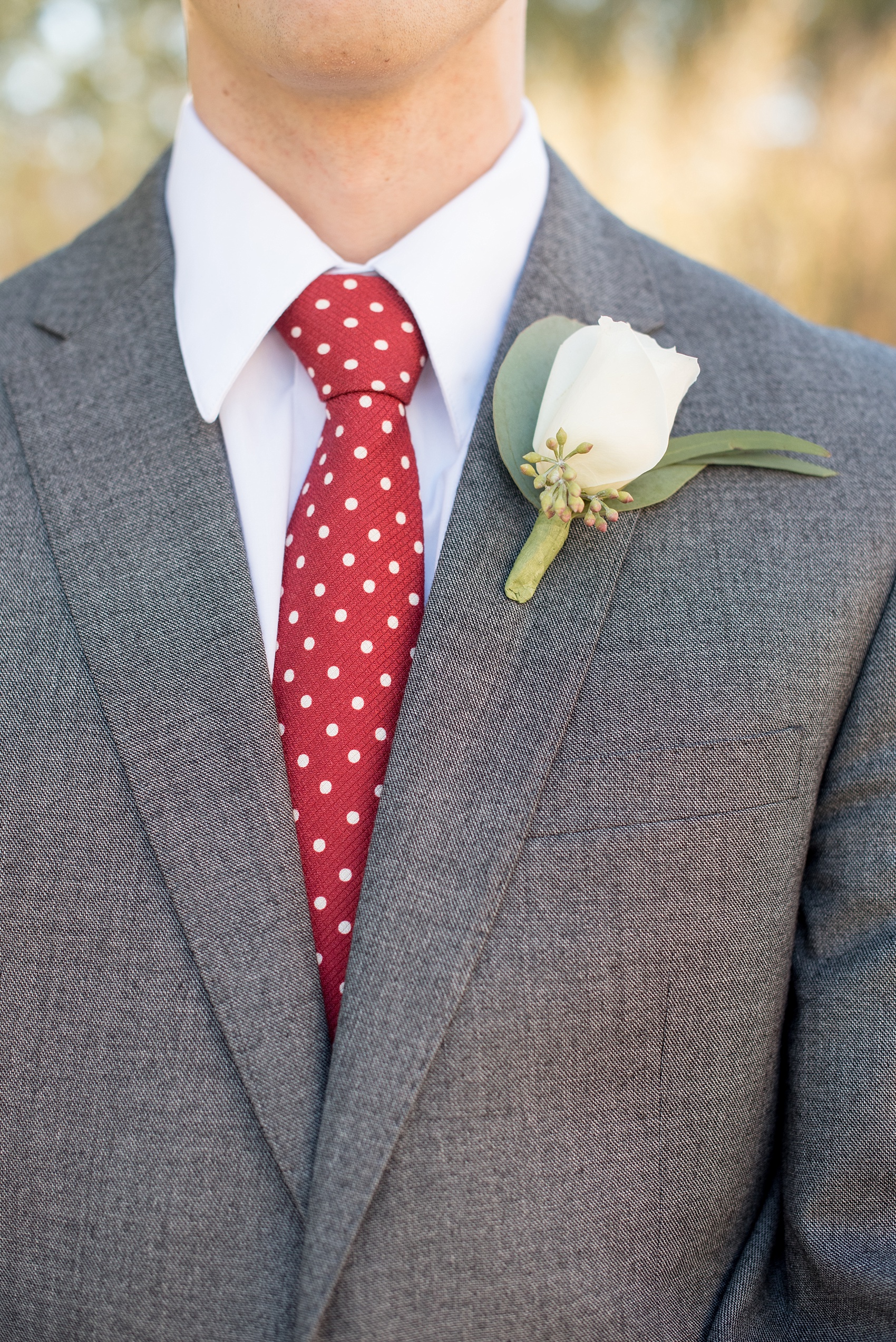 Mikkel Paige Photography photo of a wedding at The Rickhouse, Durham. The best man and groomsman wore a red and white polka dot tie and grey suit with a rose boutonniere.