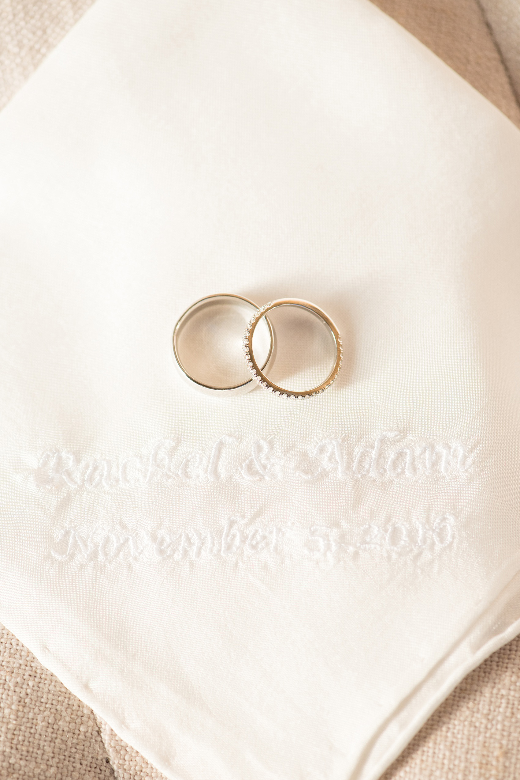 Mikkel Paige Photography photo of a wedding at The Rickhouse, Durham. A picture of the wedding bands against a custom white embroidered handkerchief with the couple's wedding date on it.