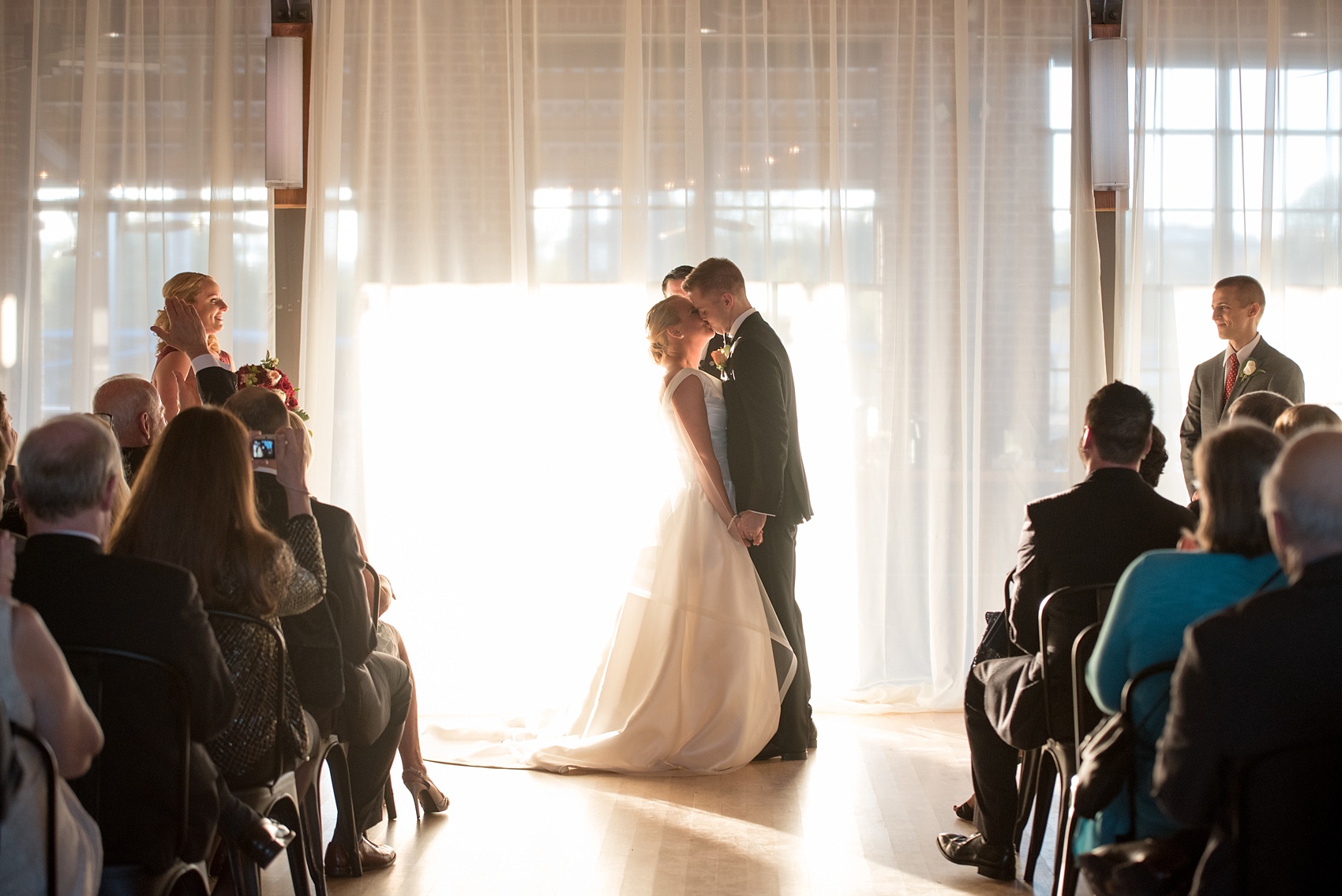 Mikkel Paige Photography photo of a wedding at The Rickhouse, Durham. A picture of the bride and groom's first kiss during their indoor ceremony.