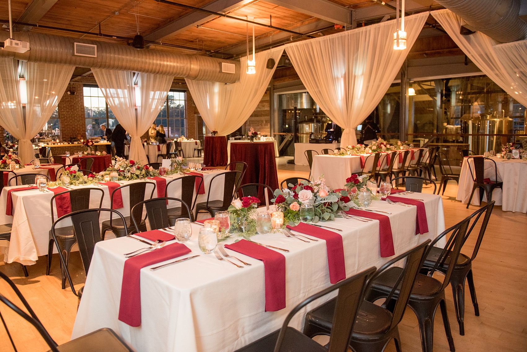 Mikkel Paige Photography photo of a wedding at The Rickhouse, NC. A picture of the rectangular and round mixed tables with burgundy linens and fall flowers and candlelight.