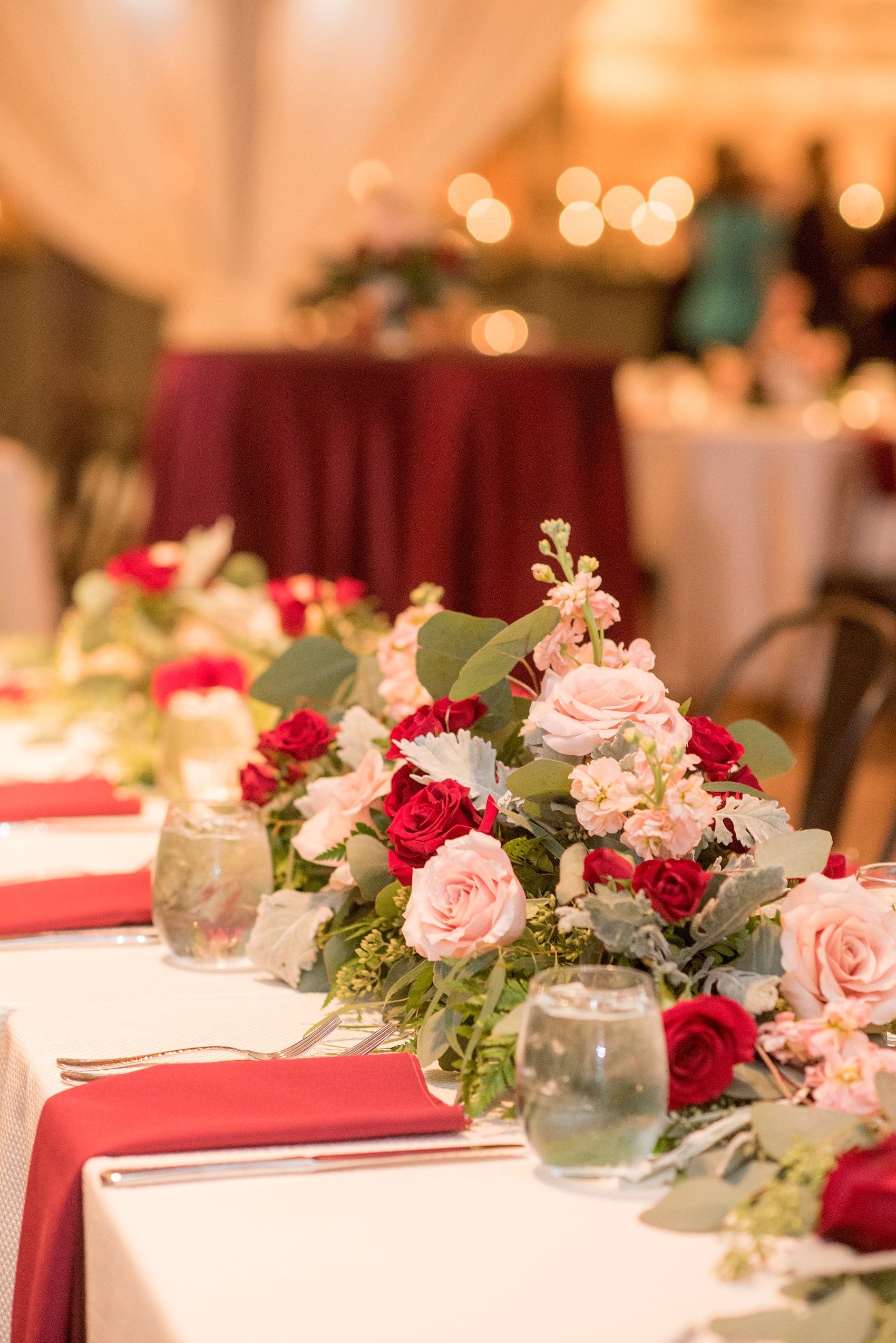 Mikkel Paige Photography photo of a wedding at The Rickhouse, NC. A picture of the rectangular and round mixed tables with burgundy linens and fall flowers and candlelight.