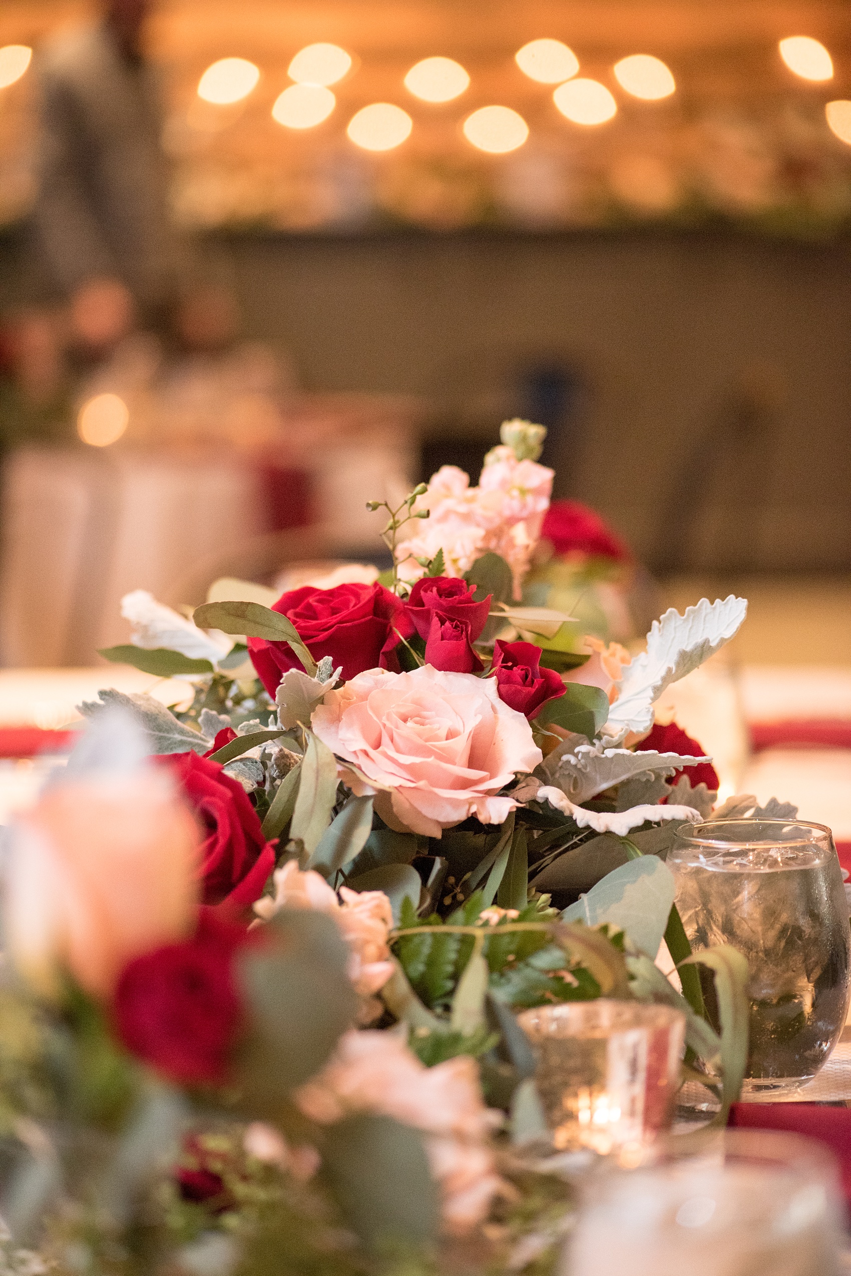 Mikkel Paige Photography photo of a wedding at The Rickhouse, NC. A picture of the rectangular and round mixed tables with burgundy linens and fall flowers and candlelight.