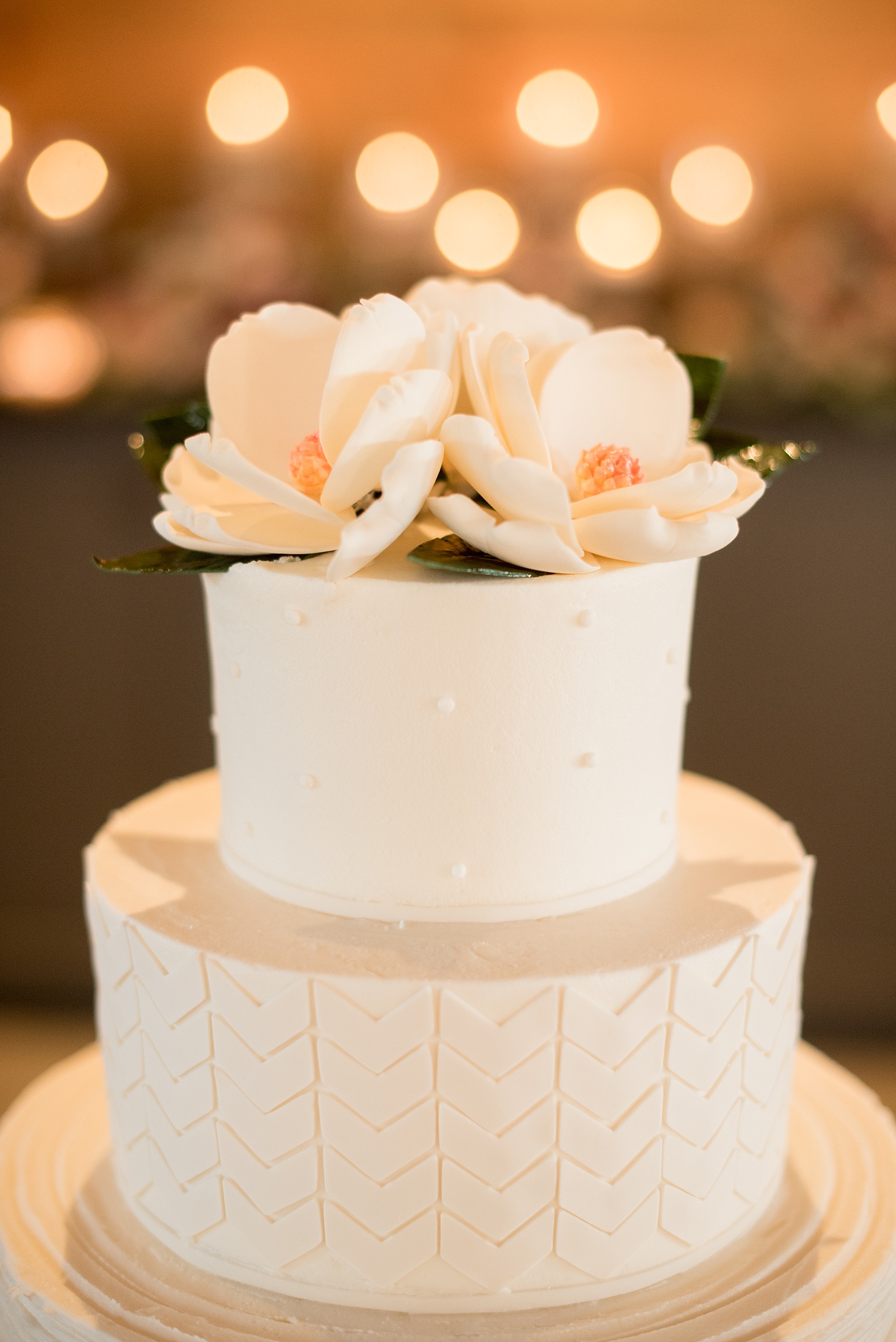 Mikkel Paige Photography photo of a wedding at The Rickhouse, NC. A picture of the white tiered fondant wedding cake topped with gumpaste magnolia sugar flowers.