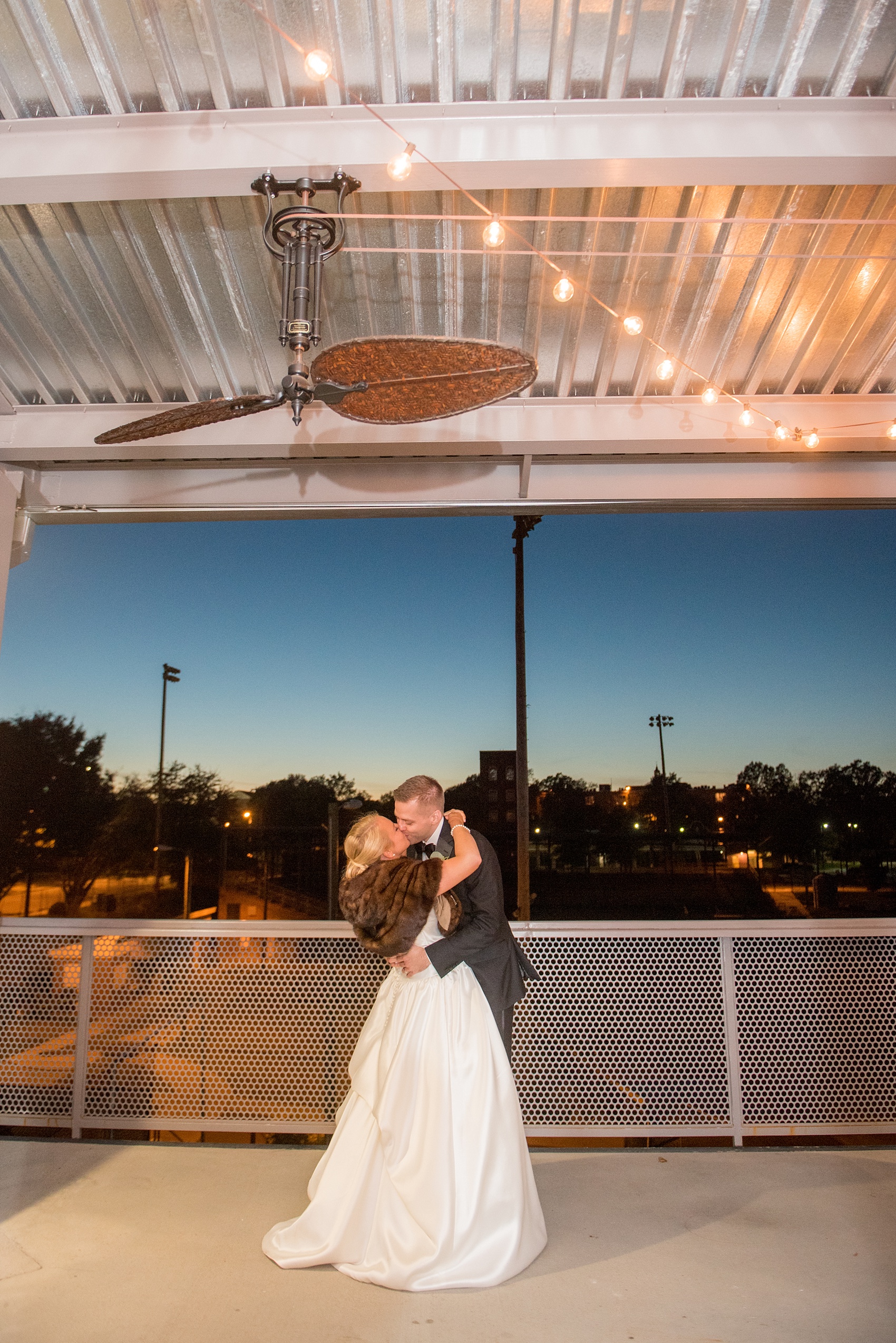 Mikkel Paige Photography photo of a wedding at The Rickhouse, NC. A picture of the bride and groom's outdoor, dusk/twilight last kiss of the night.