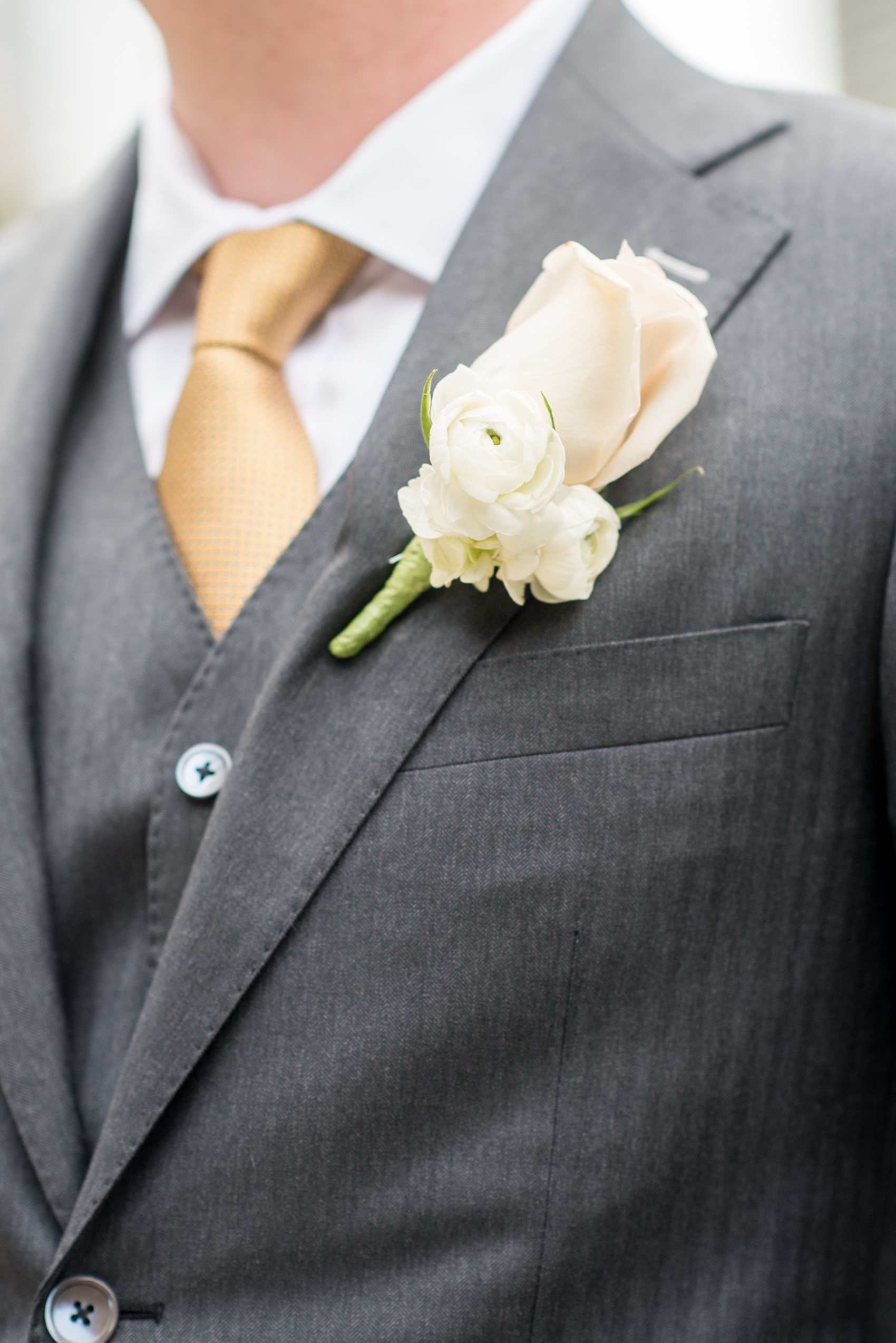 Mikkel Paige Photography photos of a wedding in downtown Chicago at The Rookery. The groom wore a three piece grey suit and had a rose and ranunculus all white boutonniere.