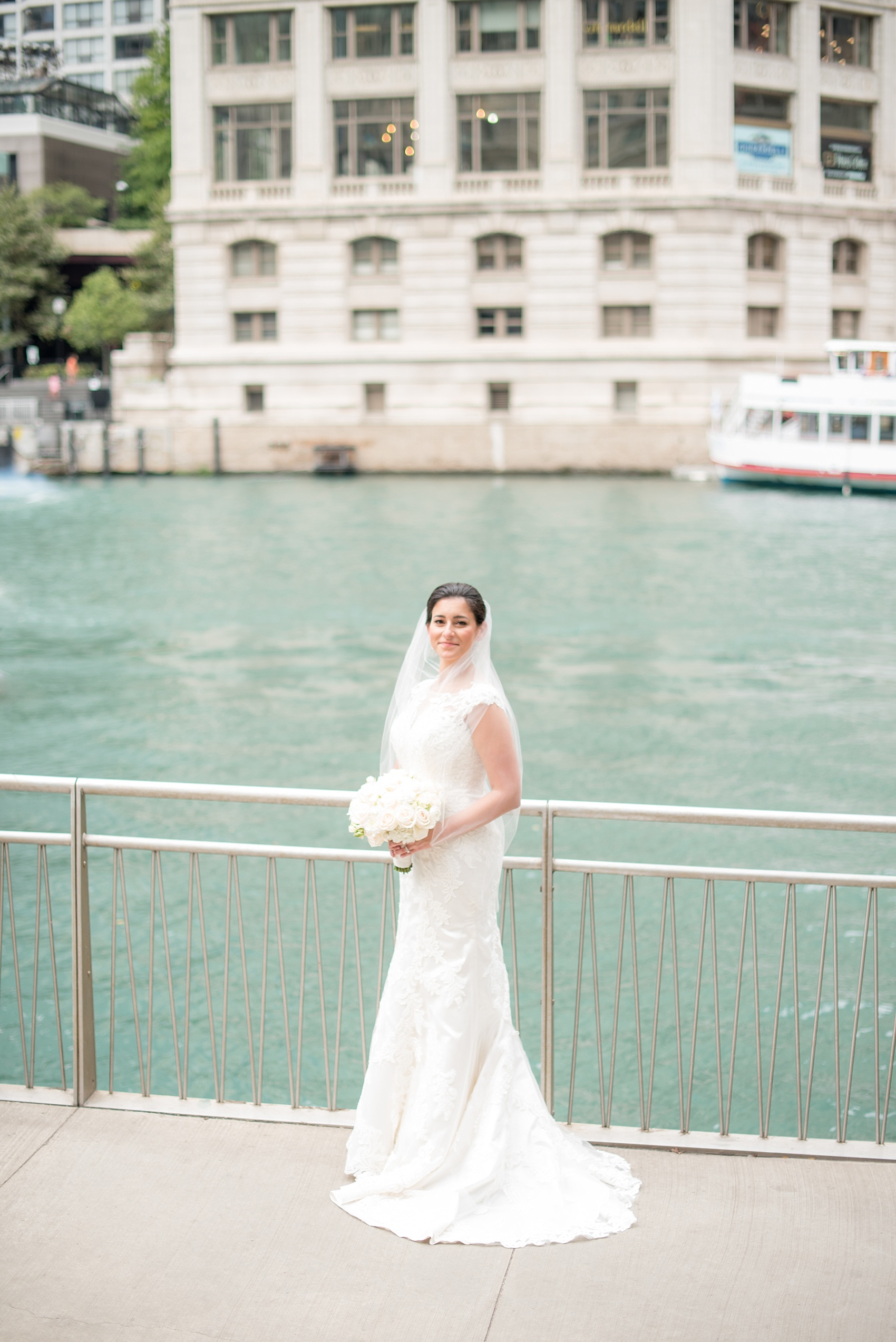 Mikkel Paige Photography photos of a wedding in downtown Chicago at The Rookery. An iconic photo of the bride in a Justin Alexander lace gown with her veil in the wind, holding a rose bouquet.