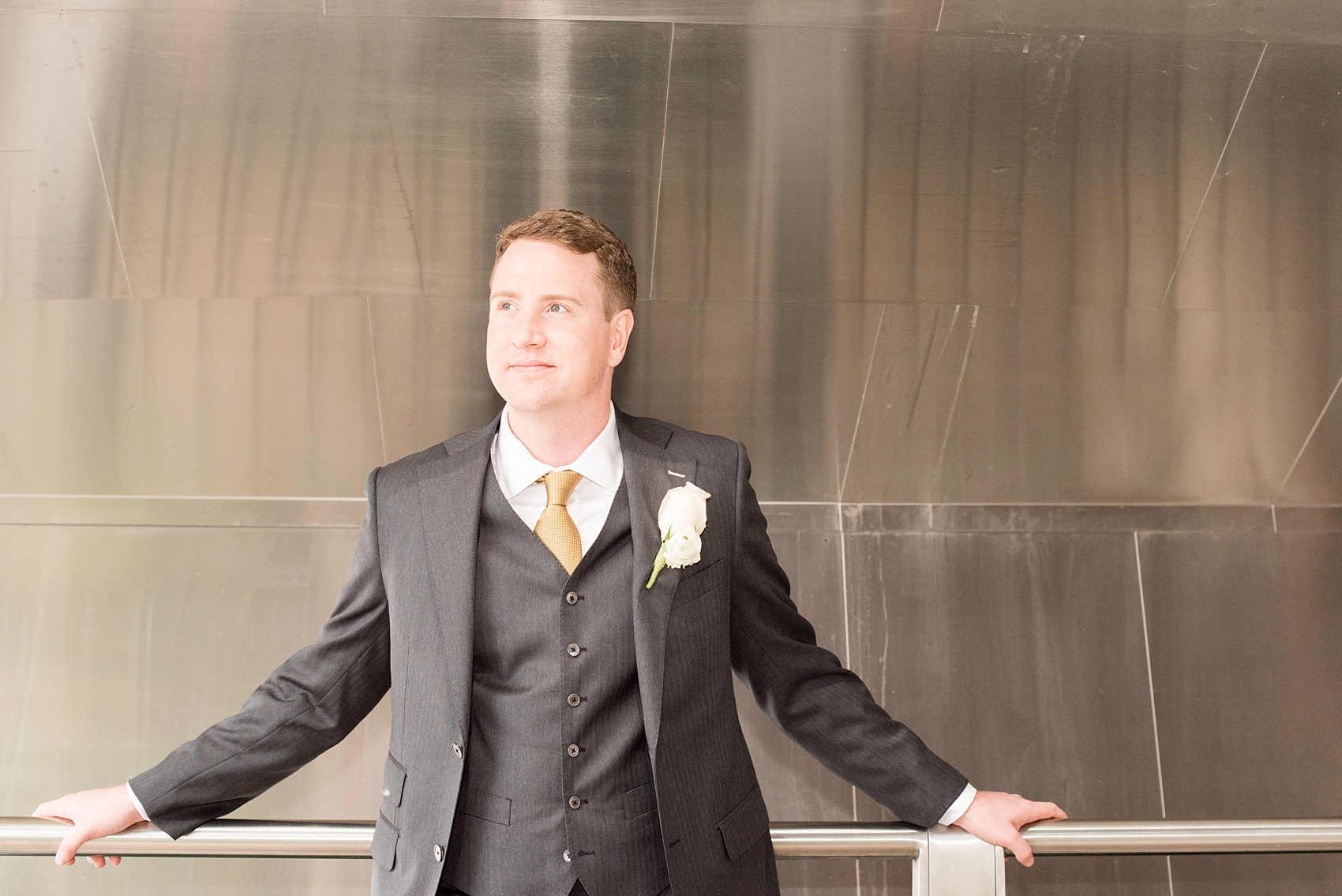 Mikkel Paige Photography photos of a wedding in downtown Chicago at The Rookery. A portrait of the groom in a three-piece grey suit with a rose and ranunculus all white boutonniere.