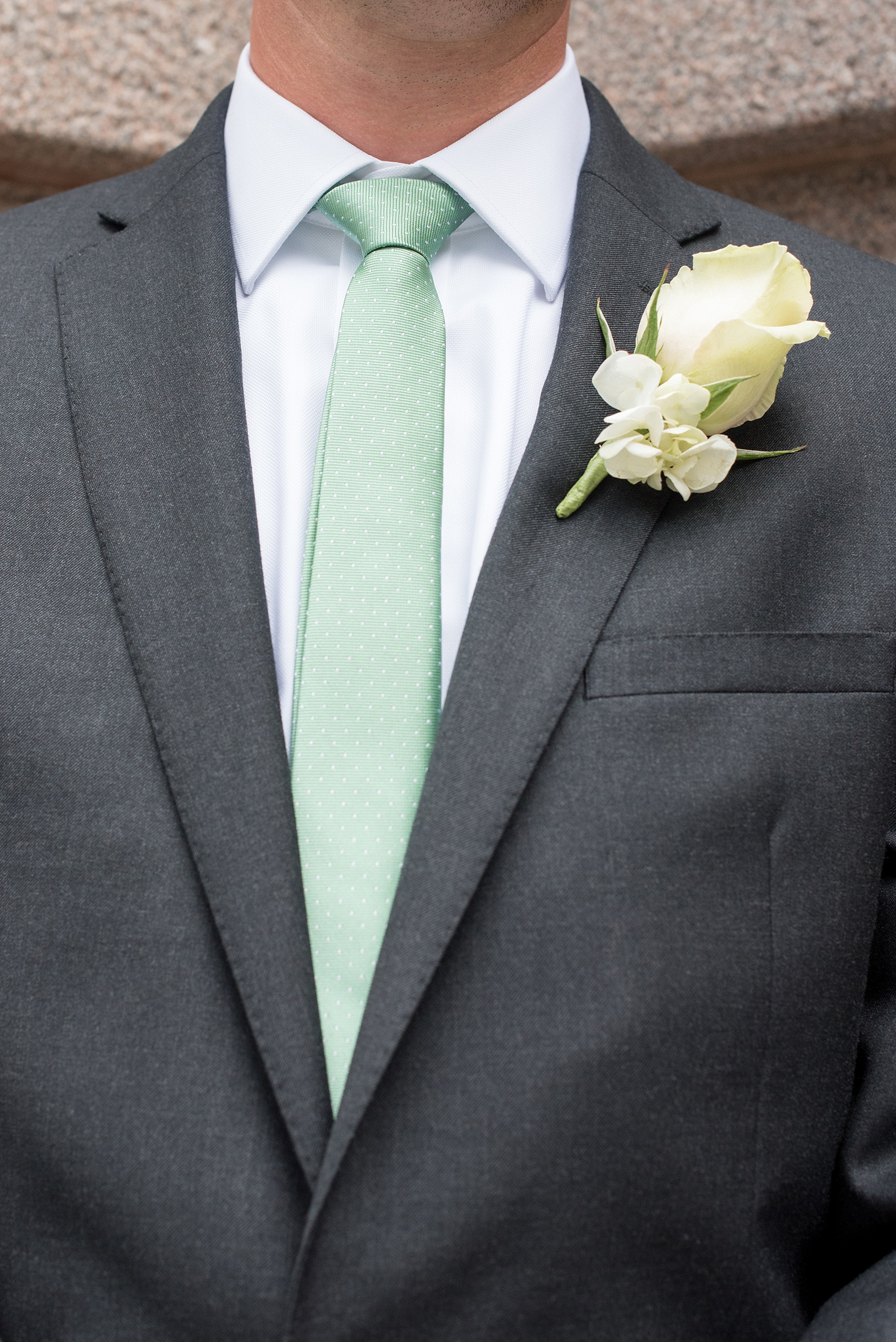 Mikkel Paige Photography photos of a wedding in downtown Chicago at The Rookery. The groomsmen wore grey suits with mint green polka dot ties and had rose and hydrangea all white boutonnieres.