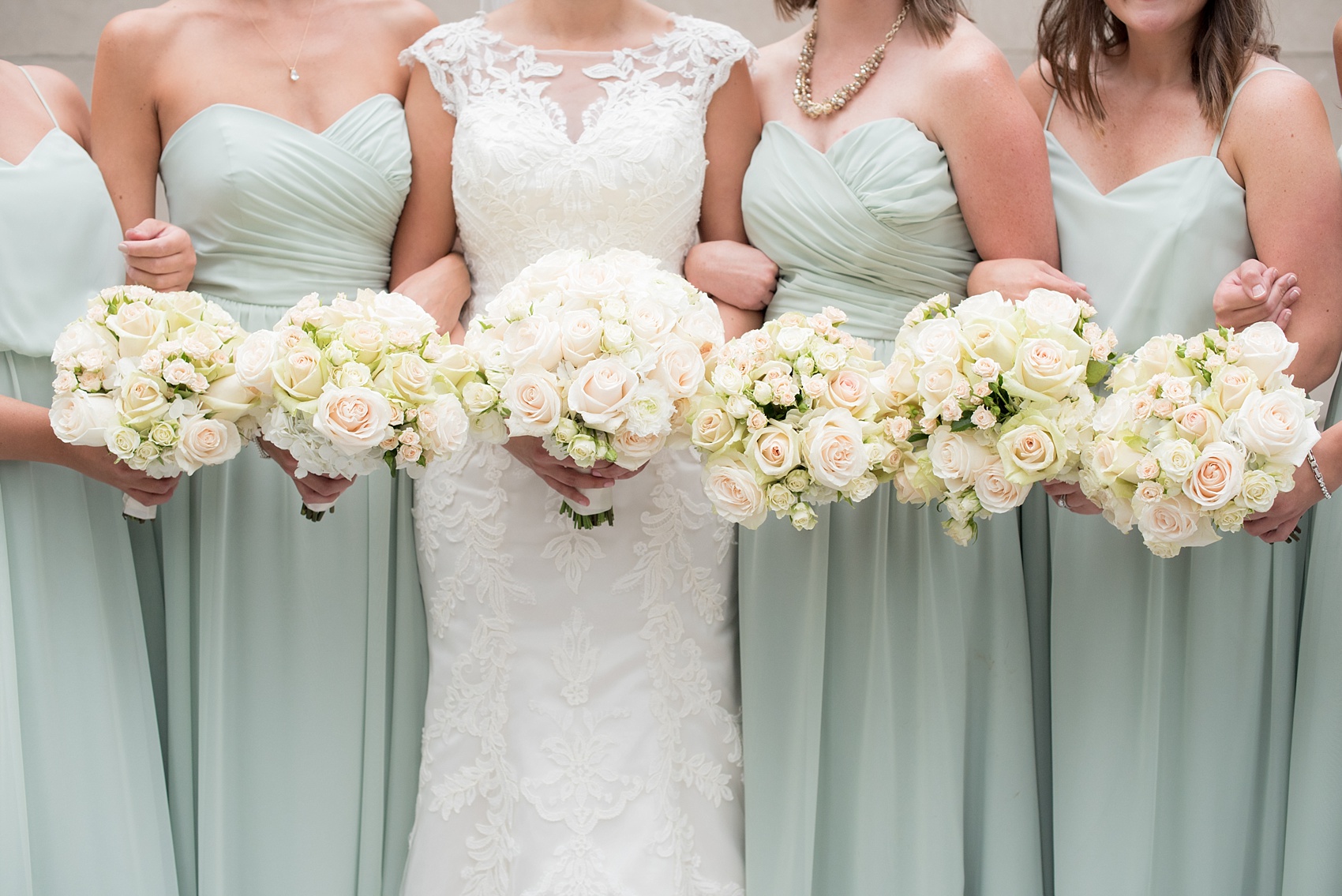 Mikkel Paige Photography photos of a wedding in downtown Chicago at The Rookery. The bride and her bridesmaids in mint green gowns by Alfred Angelo took photos by the waterfront on Riverwalk and held all white and light peach rose bouquets.