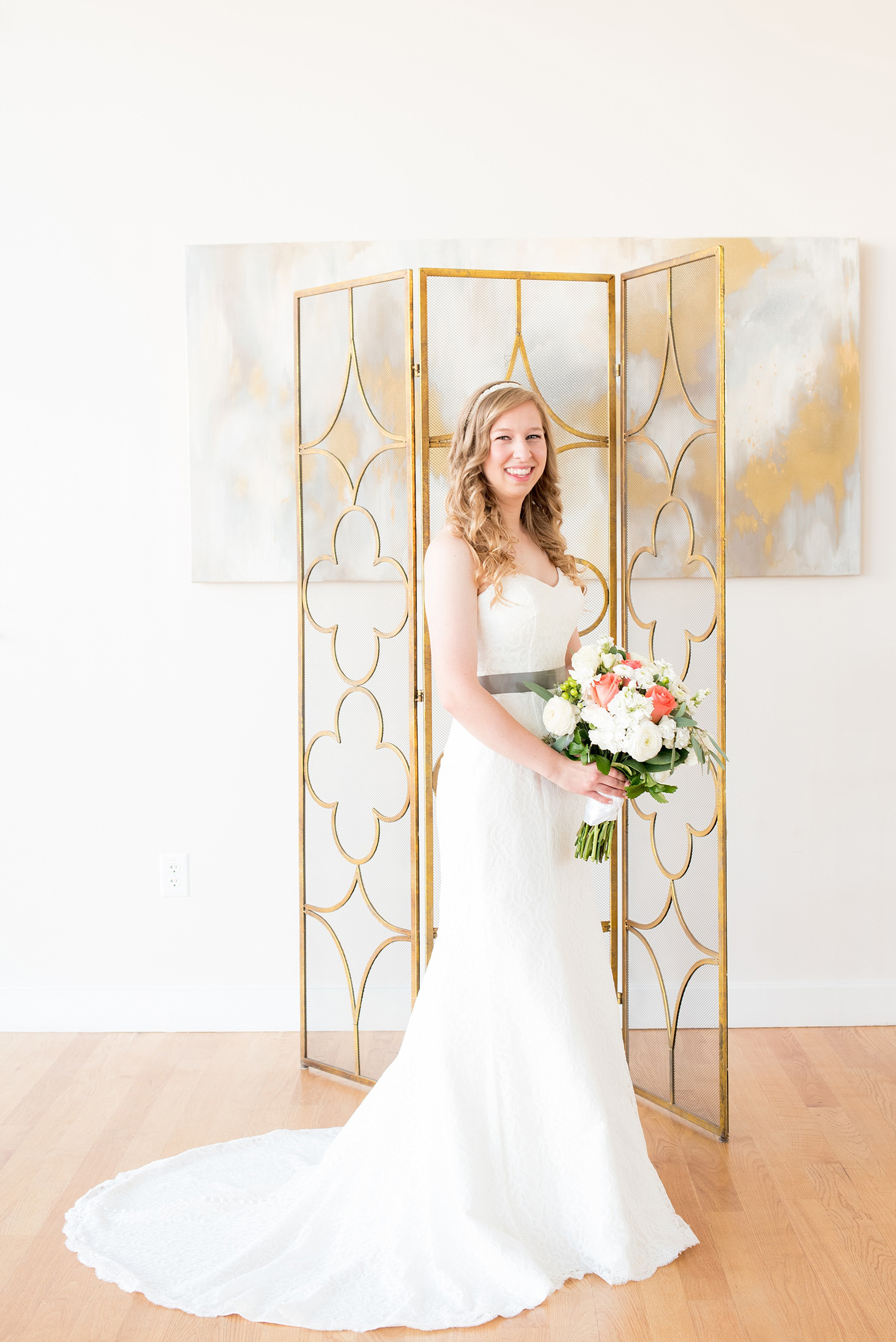 Mikkel Paige Photography photos from a wedding at The Glass Box and Stockroom at 230 in Raleigh. A picture of the bride in her lace strapless gown with grey belt and coral and white bouquet.