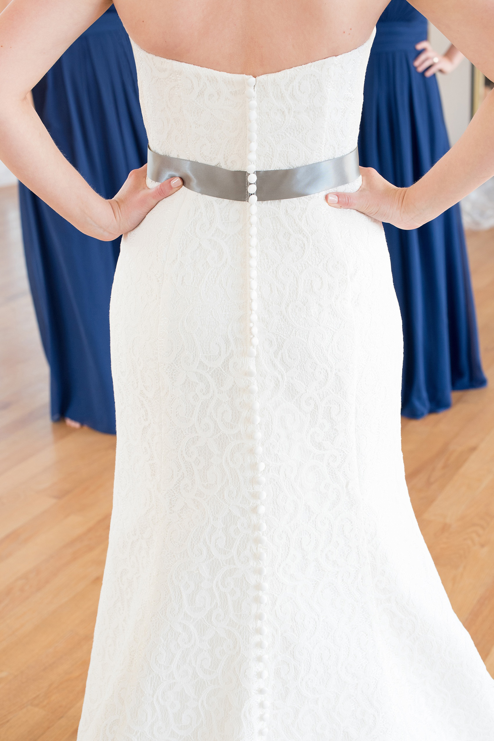 Mikkel Paige Photography photos from a wedding at The Glass Box and Stockroom at 230 in Raleigh. A unique picture of the bride in her lace gown with grey belt and coral and white bouquet.