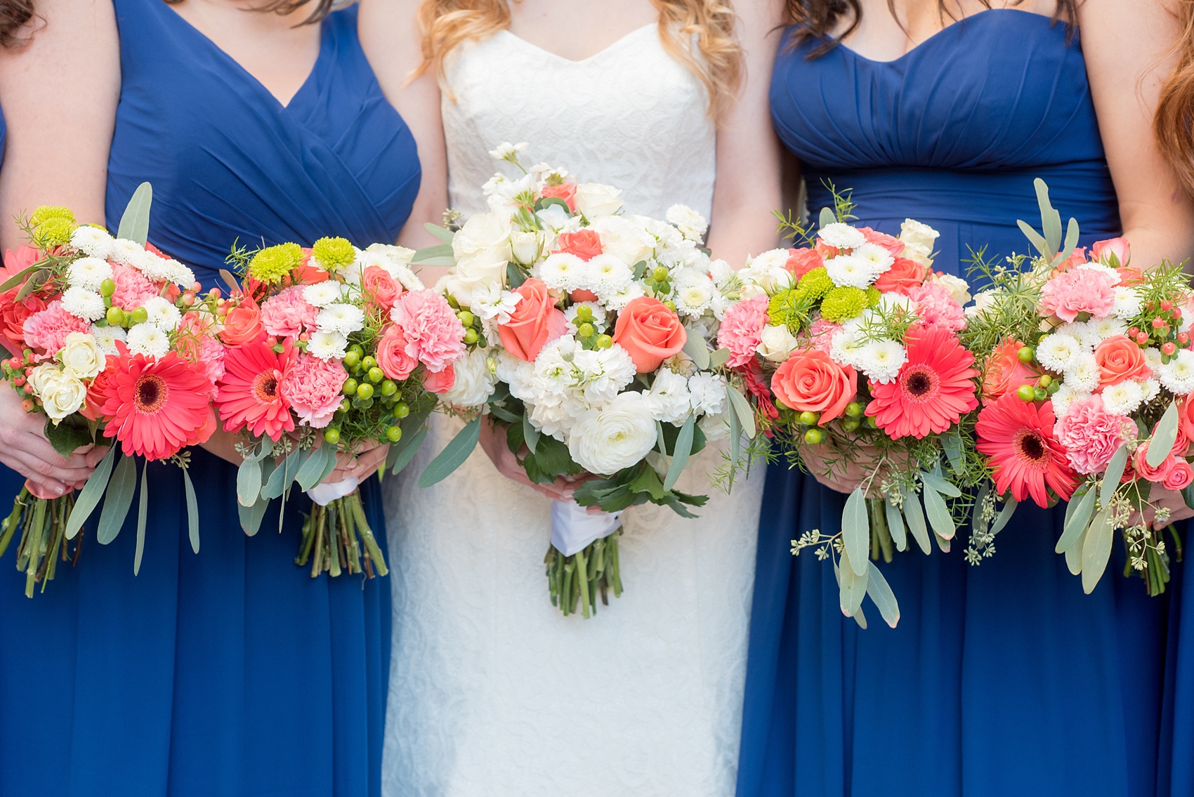 Mikkel Paige Photography photos from a wedding at The Stockroom at 230. A picture of the bride and her bridesmaids in cobalt blue in downtown Raleigh with coral and white bouquets.