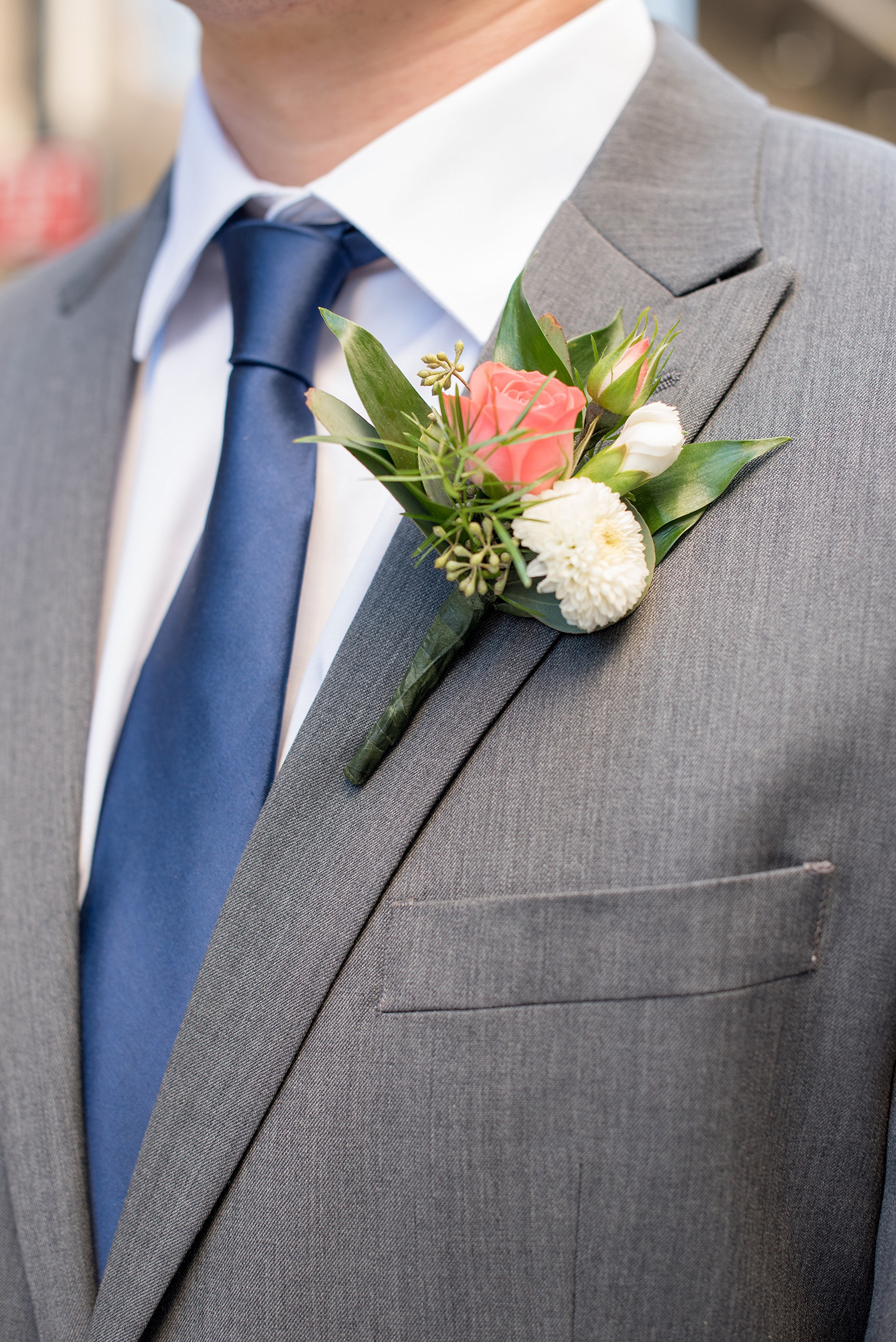 Mikkel Paige Photography photos from a fall wedding at The Stockroom at 230. A picture of the groomsmen boutonnieres with coral and white flowers.