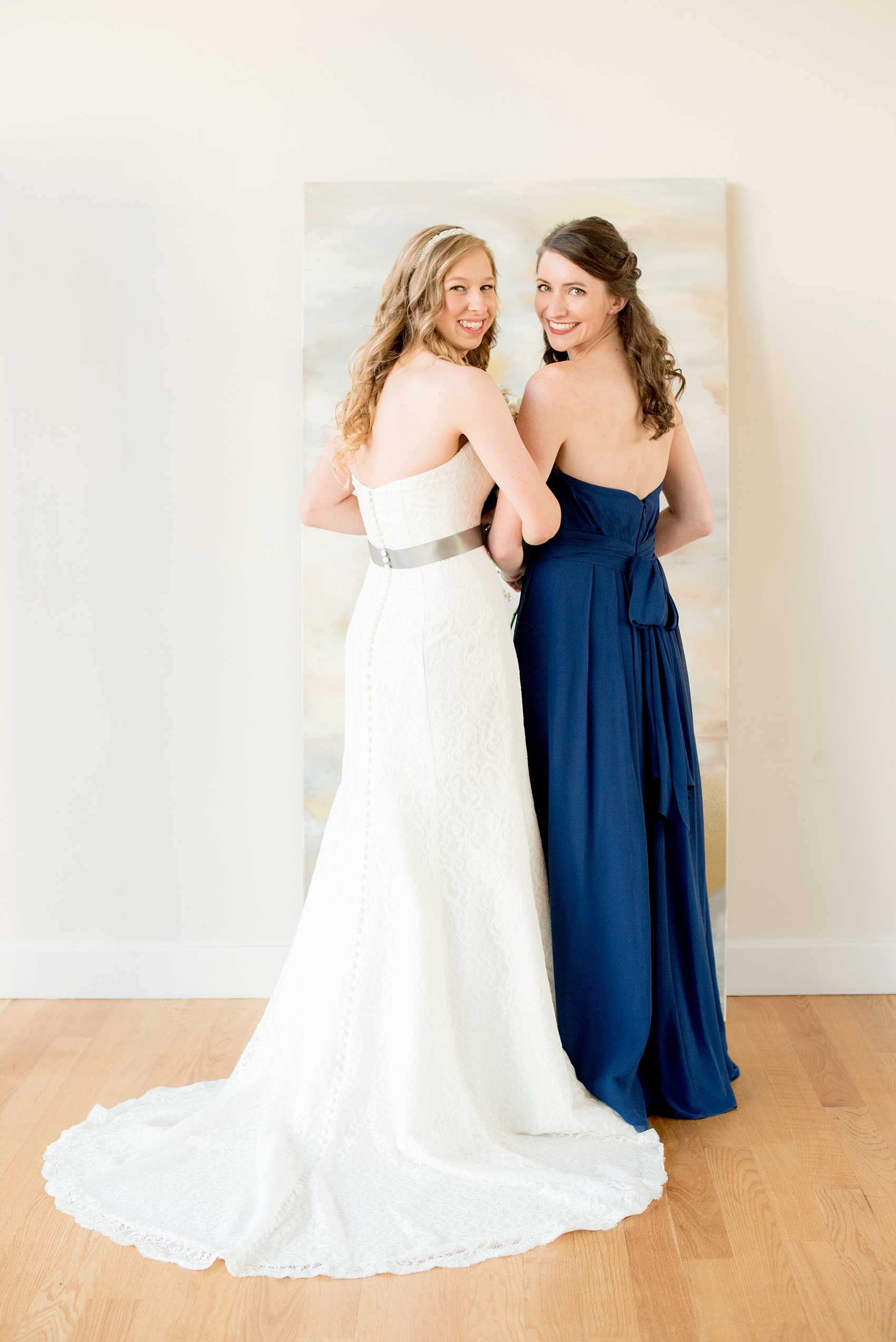 Mikkel Paige Photography photos from The Glass Box in downtown Raleigh. A cute playful picture of the bride and her bridesmaid in cobalt blue.