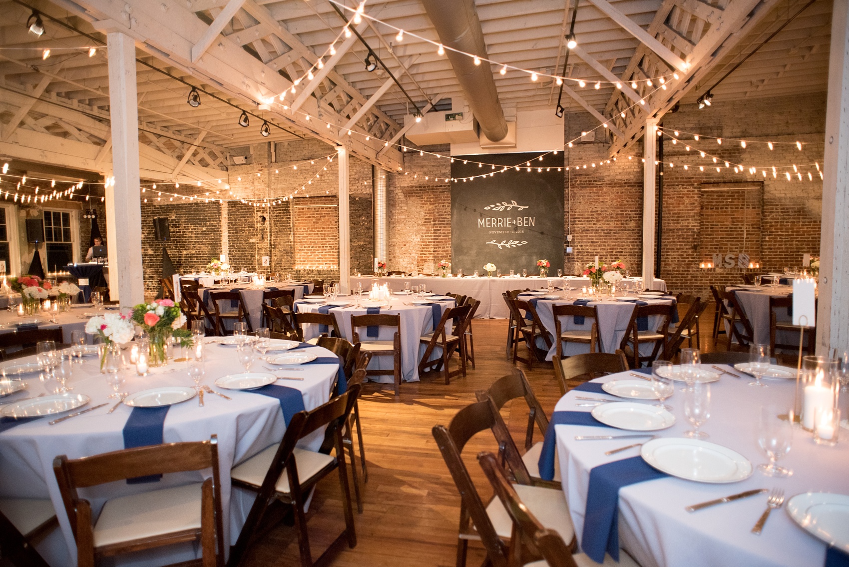 Mikkel Paige Photography photos from a wedding reception at The Stockroom at 230 in downtown Raleigh. A picture of the round tables with blue linens, with custom chalk art.