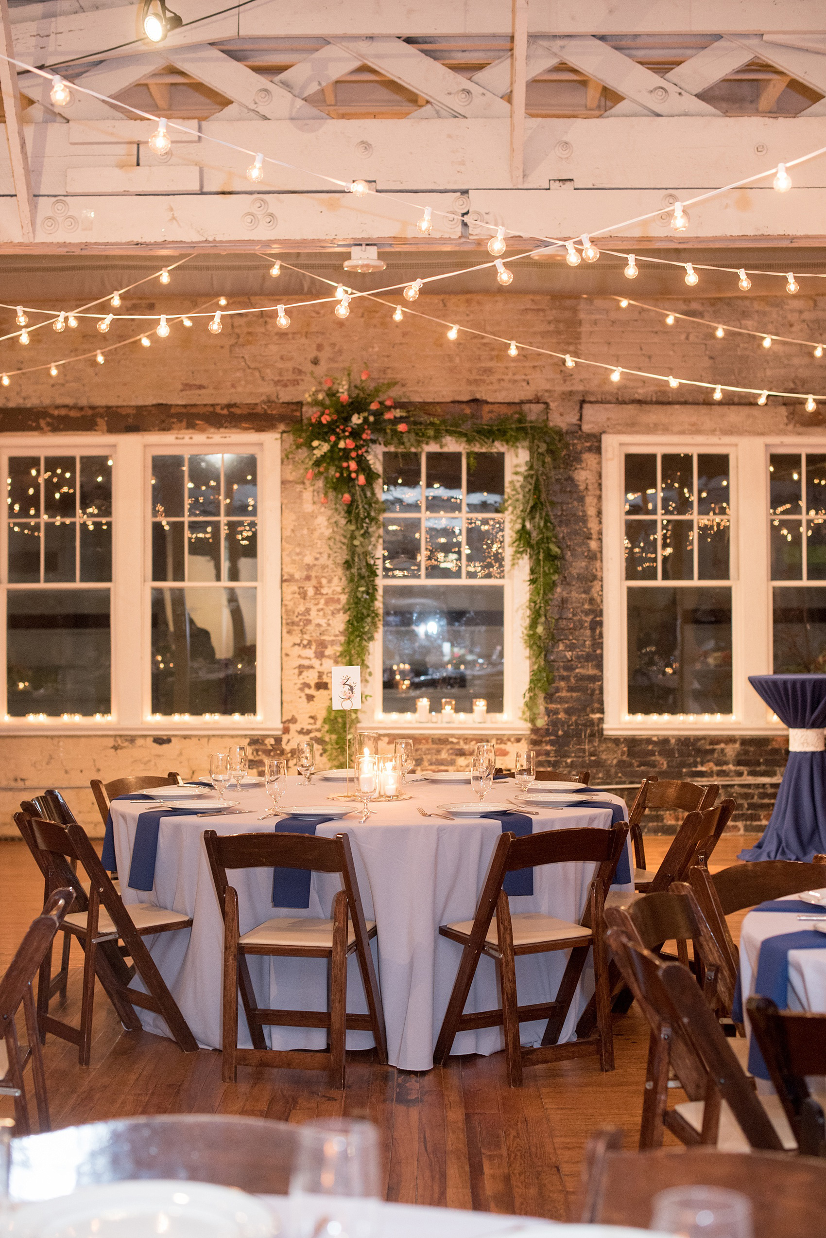 Mikkel Paige Photography photos from a wedding reception at The Stockroom at 230 in Raleigh. A picture of the centerpieces with green, white and coral flowers and Rifle Paper Co table numbers.