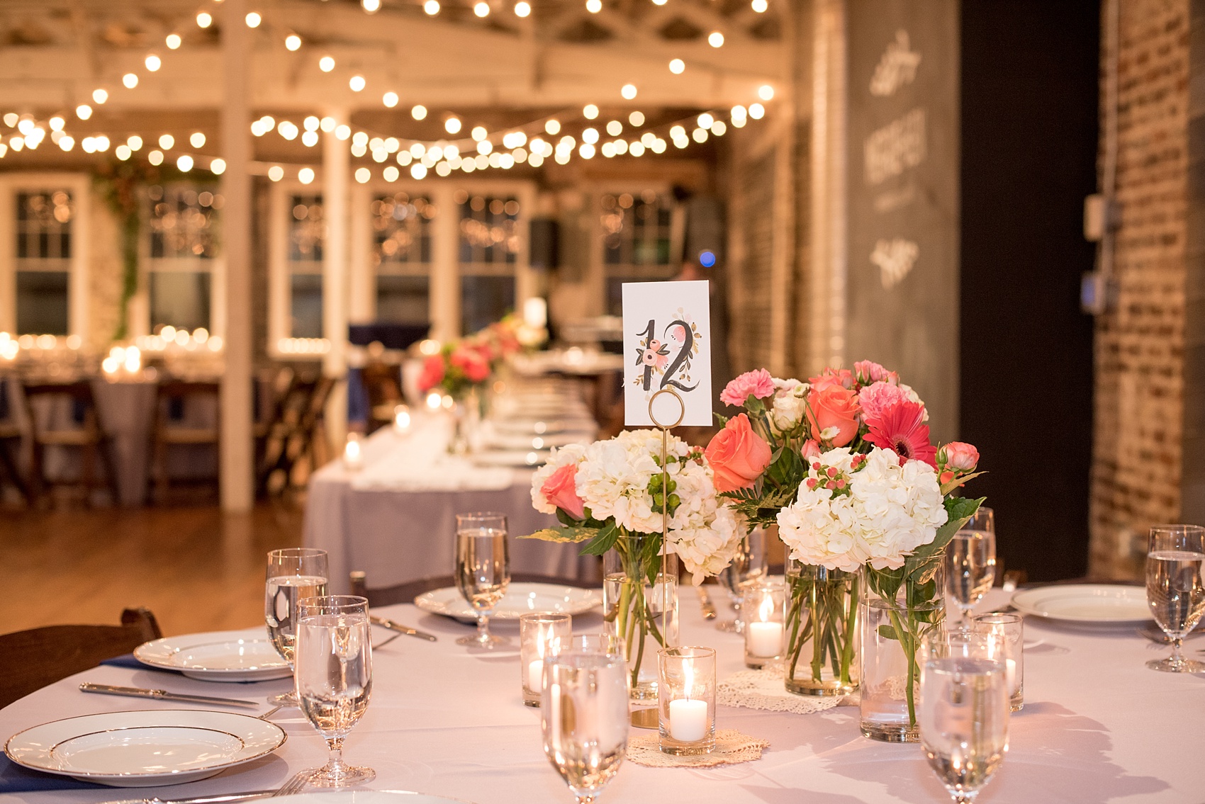 Mikkel Paige Photography photos from a wedding reception at The Stockroom at 230 in Raleigh. A picture of the centerpieces with green, white and coral flowers and Rifle Paper Co table numbers.