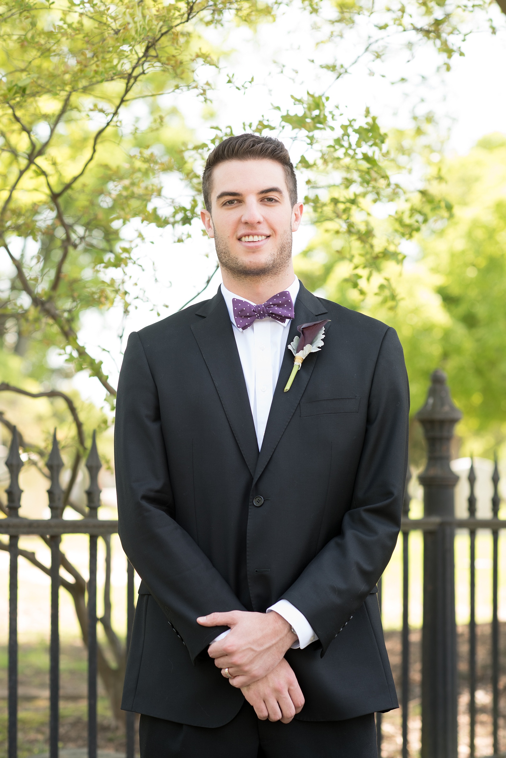 Mikkel Paige Photography pictures of a gay All Saints Chapel wedding in Raleigh, NC. The groom wore a purple polka dot bow tie with calla lily boutonnière.