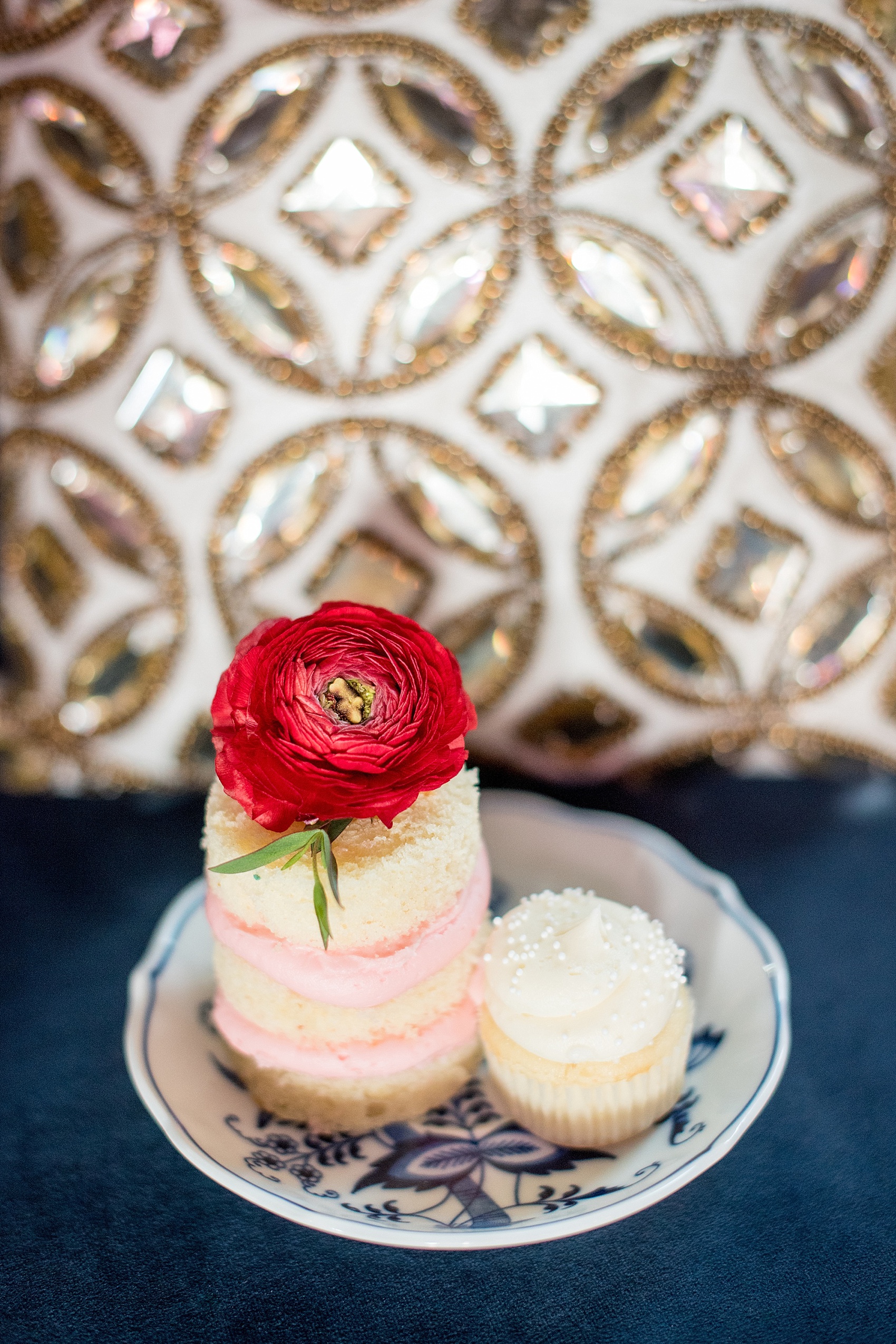 All Saints Chapel Raleigh bridal photos with an inspirational tea for Galentine's Day with pink and mini cakes topped with a red ranunculus flower by Flower and Flour NC.