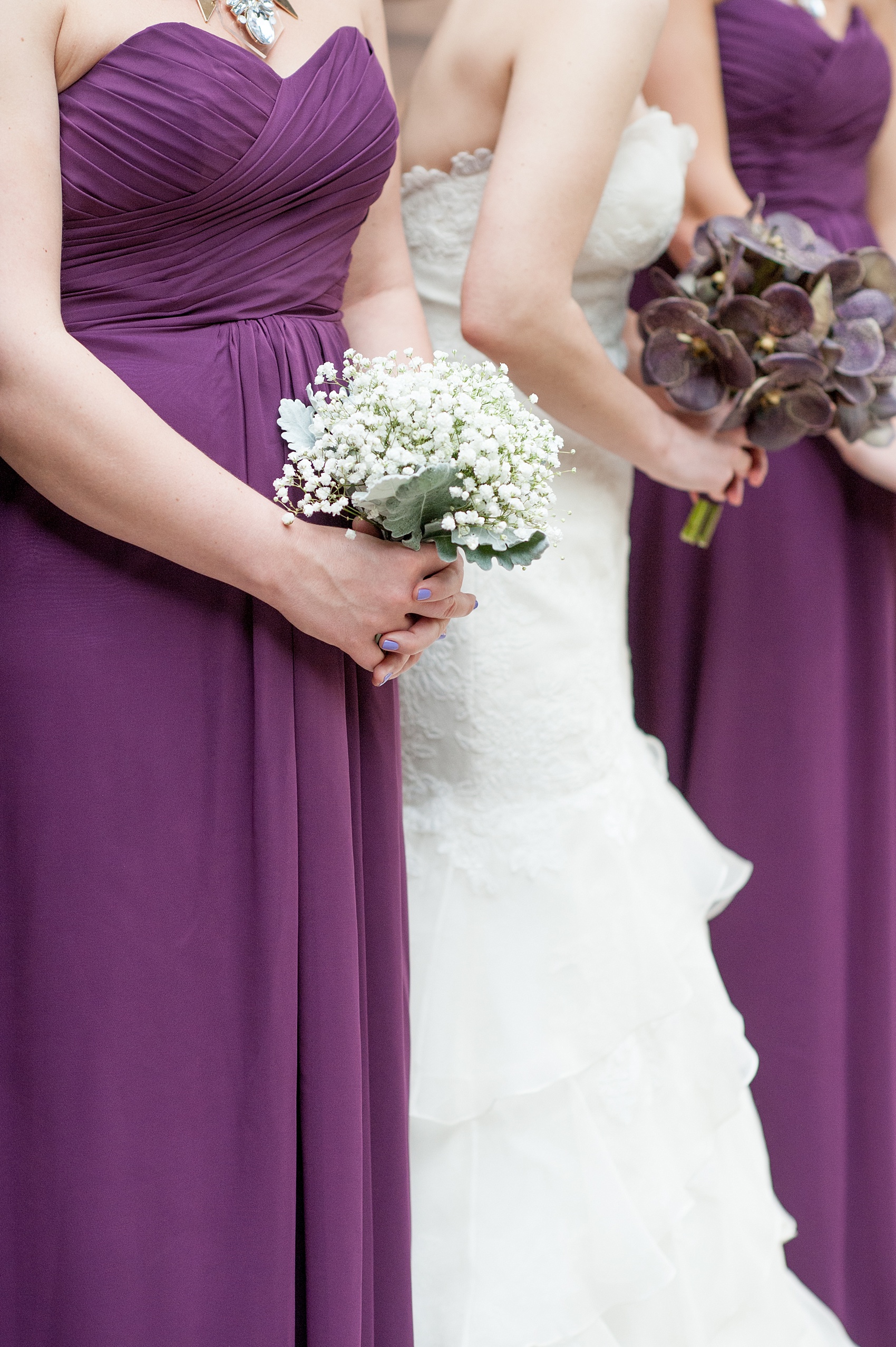 Mikkel Paige Photography Brooklyn Winery wedding photos. Picture of a bridesmaid in purple chiffon gown holding a simple bouquet's Breath flowers next to the brides orchid bouquet.