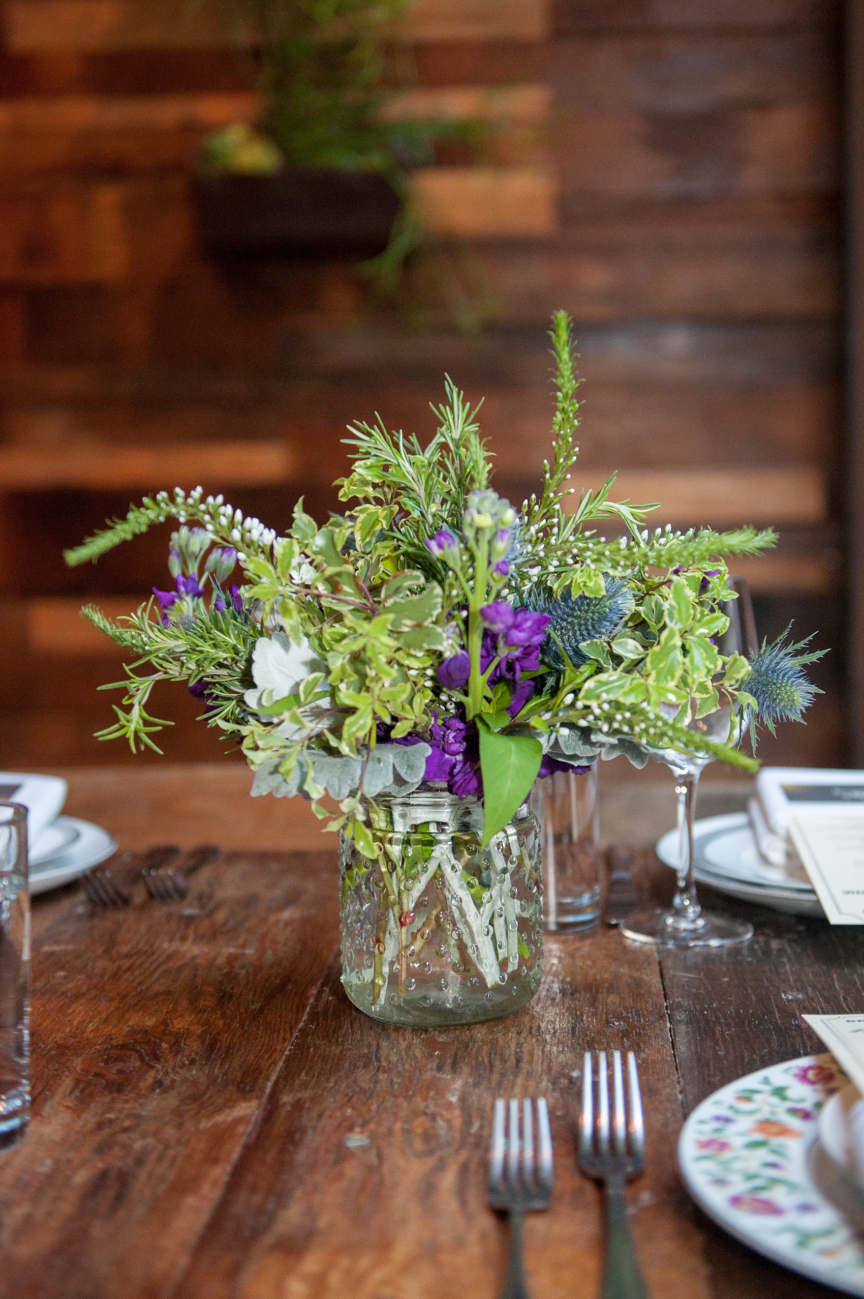 Mikkel Paige Photography Brooklyn Winery wedding photos. Picture of the wooden farm tables with purple and green floral centerpieces.