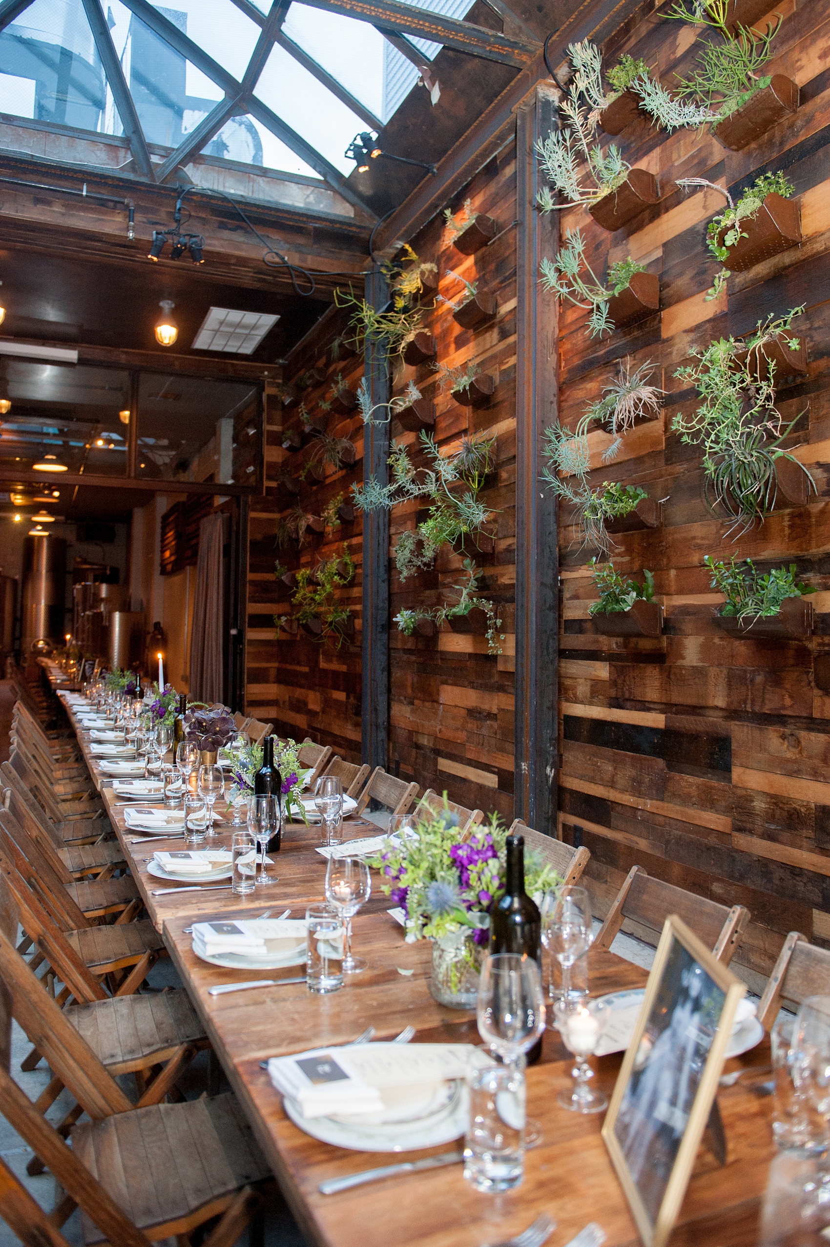 Mikkel Paige Photography Brooklyn Winery wedding photos. Picture of the wooden farm tables with purple and green floral centerpieces.