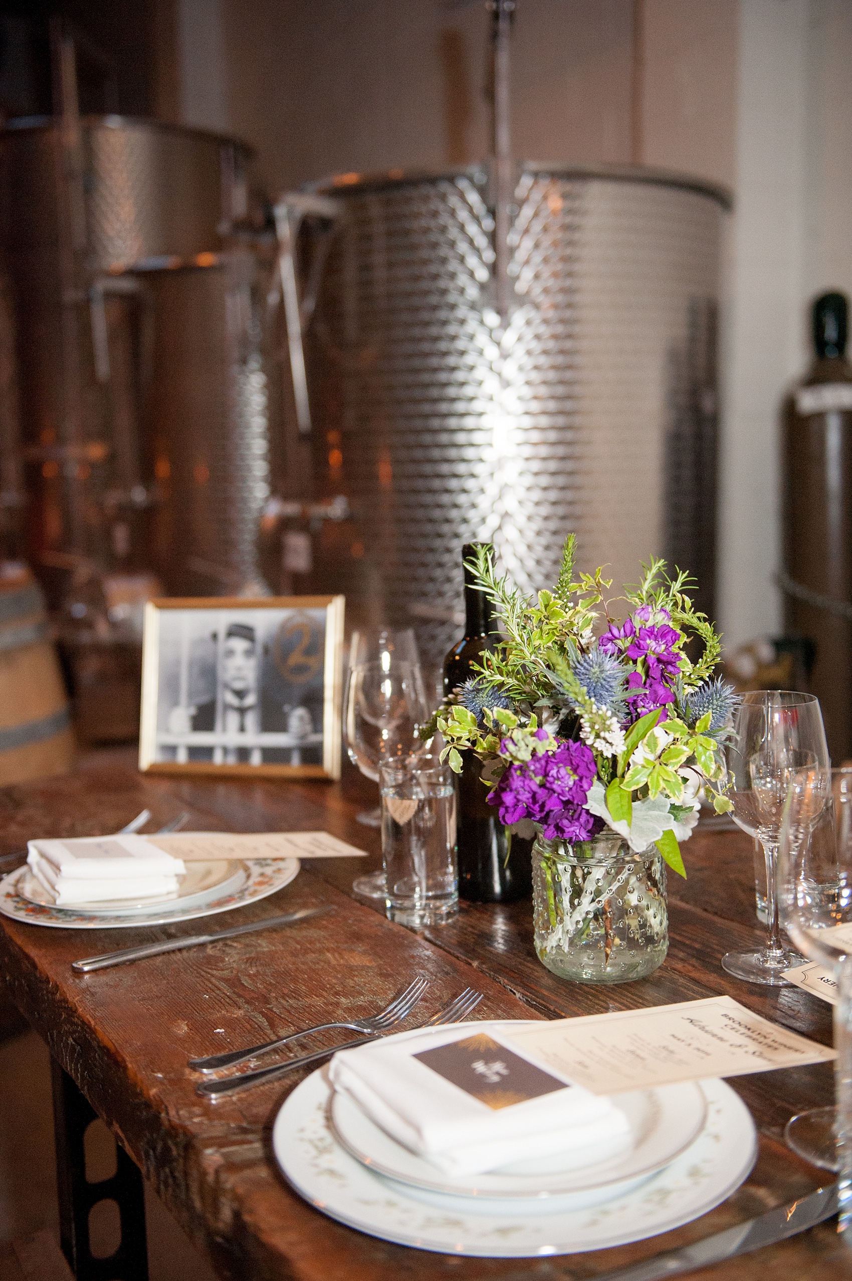 Mikkel Paige Photography Brooklyn Winery wedding photos. Picture of the wooden farm tables with purple and green floral centerpieces and unique black and white vintage table number frames.