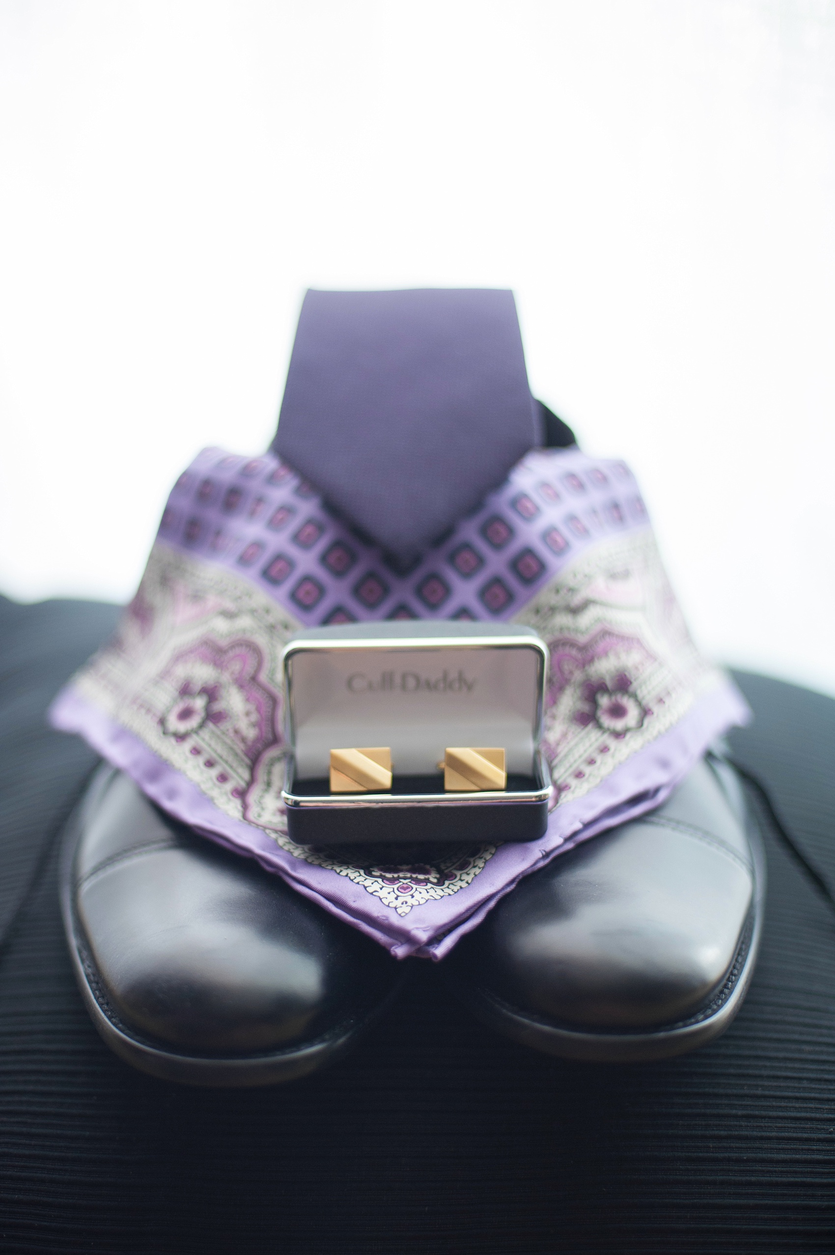 Mikkel Paige Photography Brooklyn Winery wedding photos. Detail picture of the groom's deep purple jewel-tone tie and paisley pattern lavender pocket square with gold square cufflinks and black shoes.