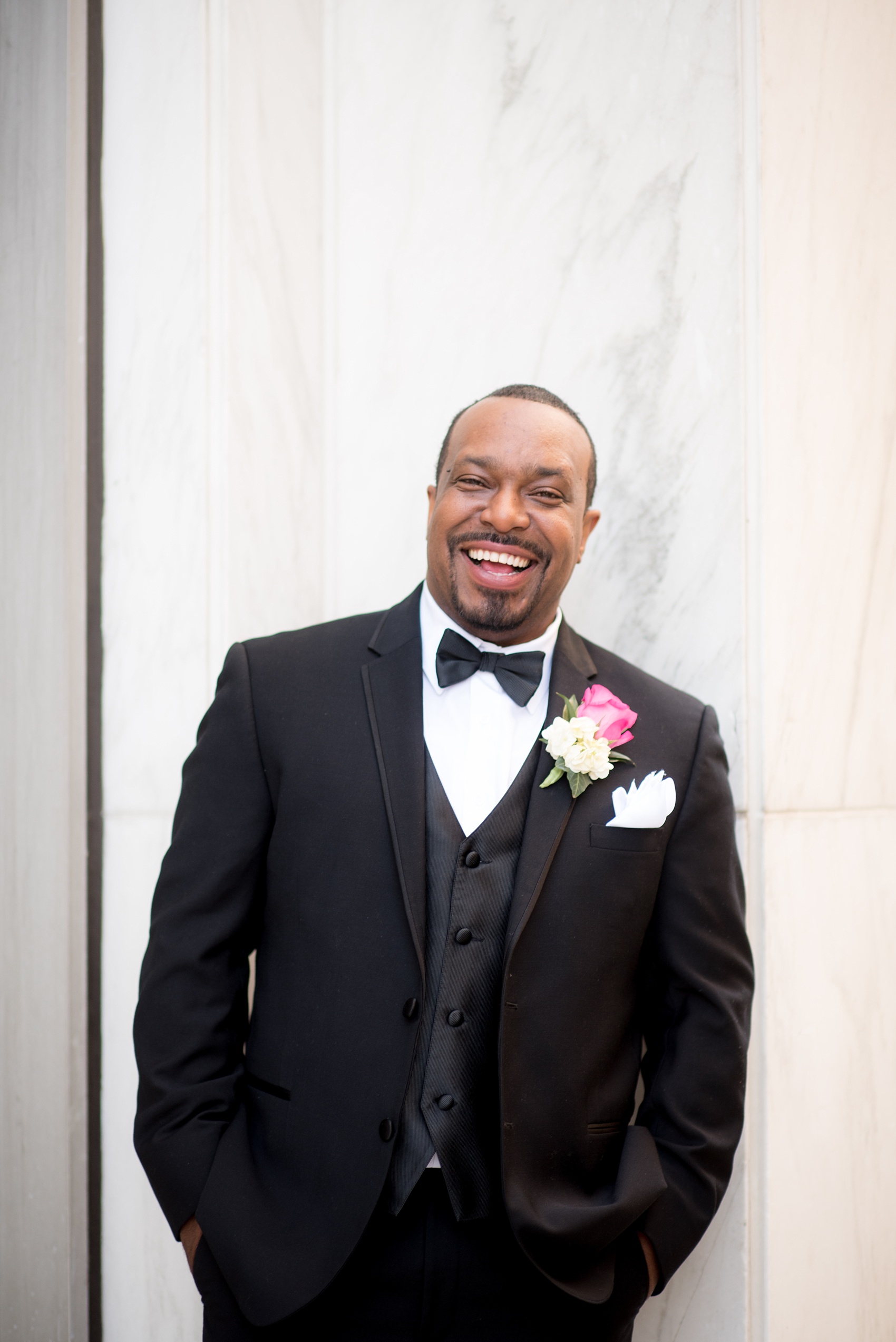 Mikkel Paige Photography photos of a small wedding at The Stockroom at 230 in downtown Raleigh, North Carolina. Image of the groom in a black tuxedo and pink rise boutonniere.
