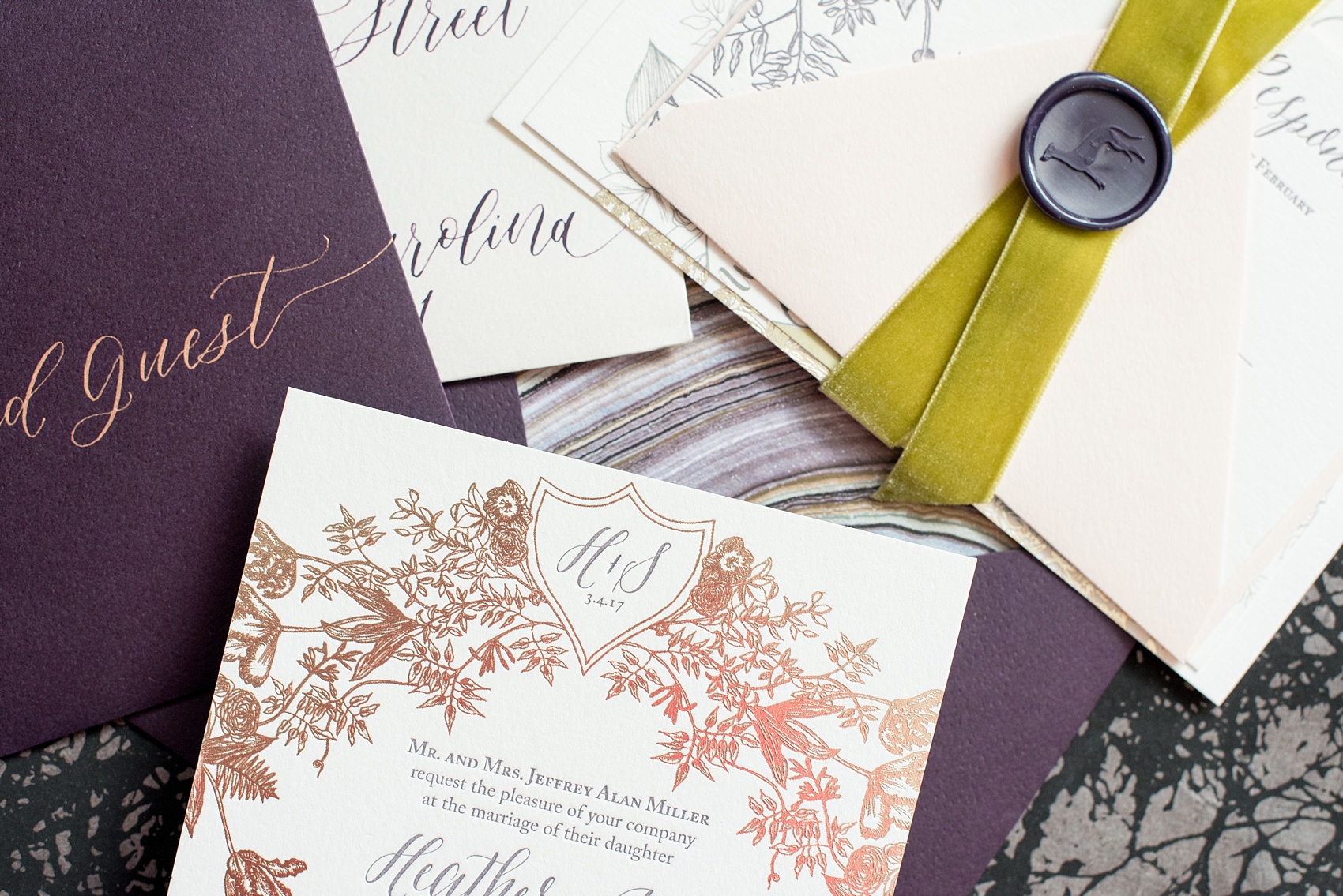 Mikkel Paige Photography image of a wedding invitation suite in purple, grey and copper by One and Only Paper. Calligraphy by Quietude Co in Raleigh, NC. Velvet yellow-green chartreuse ribbon and custom wax seals with the couples greyhound dog were included. The envelope liner was agate gem marble inspired.