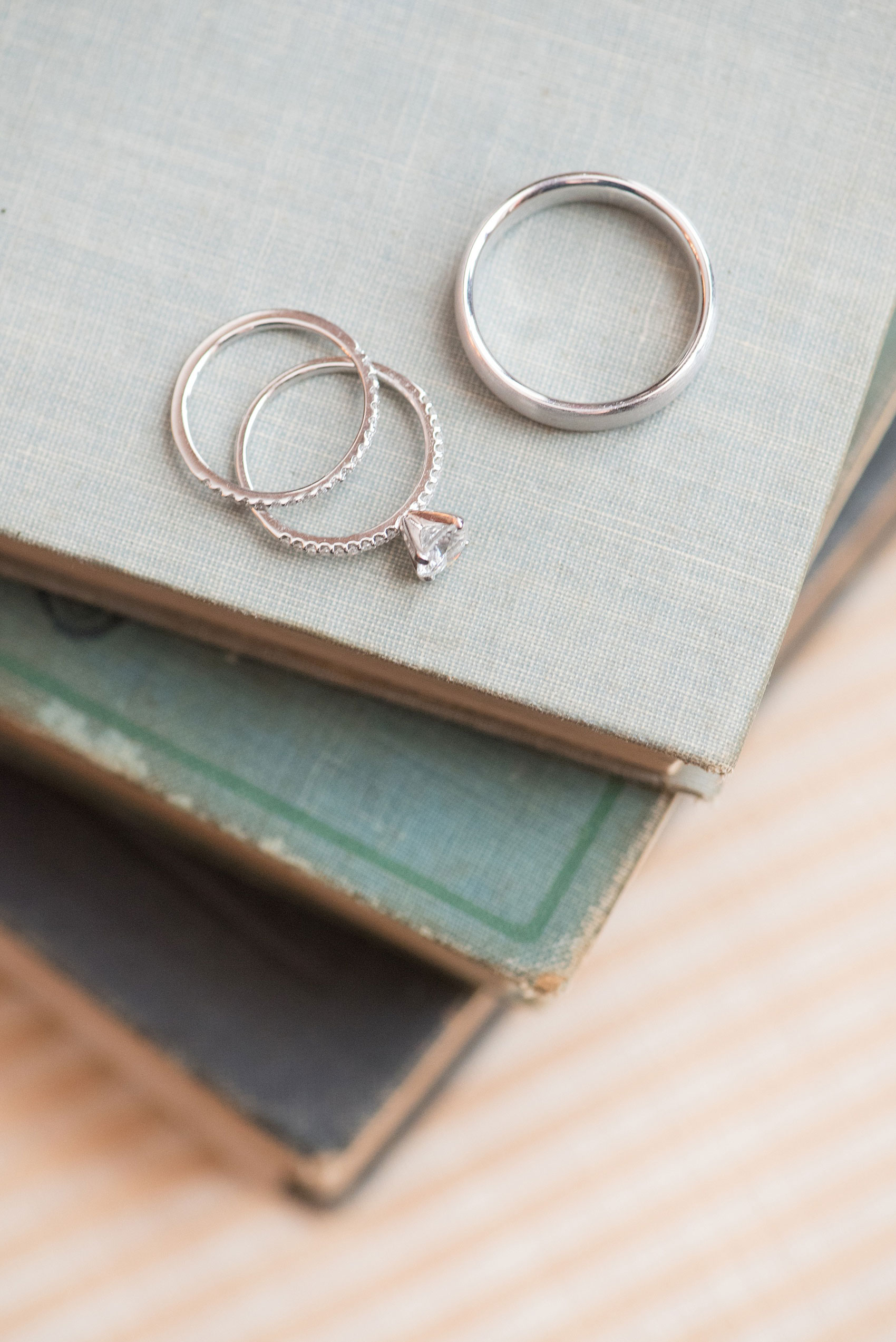 The Sutherland Wedding Photos by Mikkel Paige Photography. A detail picture of the bride and groom's white gold wedding rings on top of vintage books.