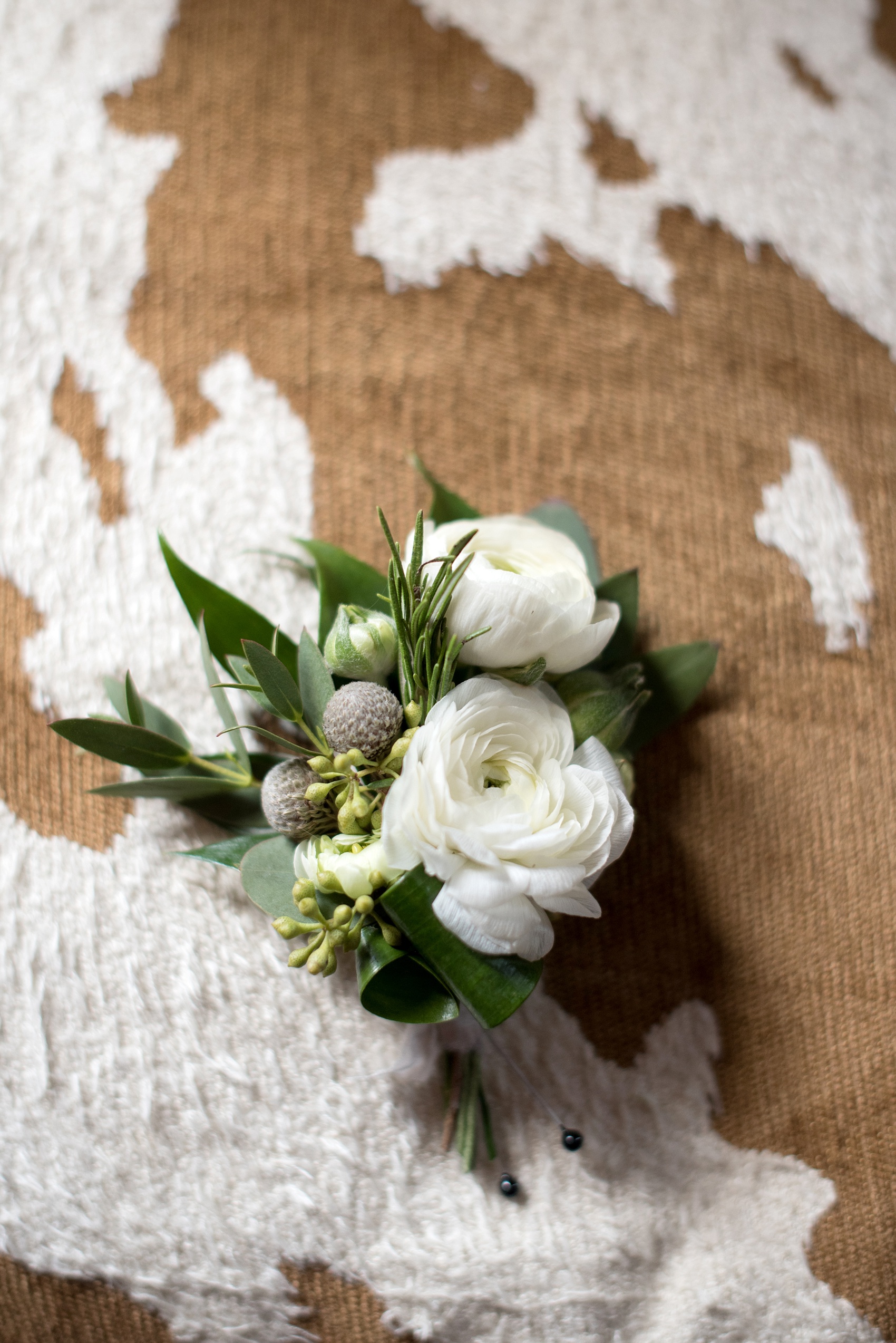 The Sutherland Wedding Photos by Mikkel Paige Photography. Detail picture of a white and green ranunculus, silver brunia and eucalyptus groom boutonniere by Eclectic Sage. Planning by A Southern Soiree.