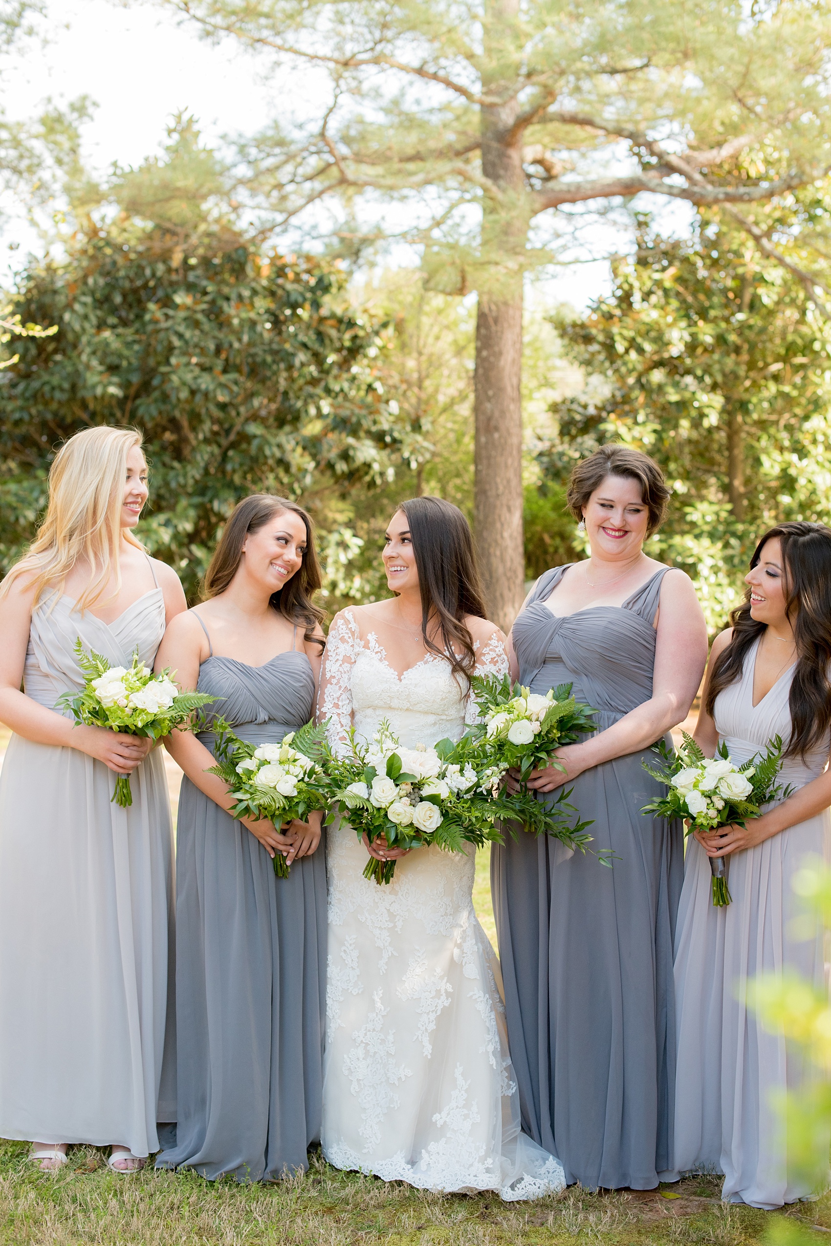 The Sutherland Wedding Photos by Mikkel Paige Photography. Candid bridal party picture with the bride in lace Pronovias and bridesmaids party in various shades of grey gowns. Planning by A Southern Soiree.