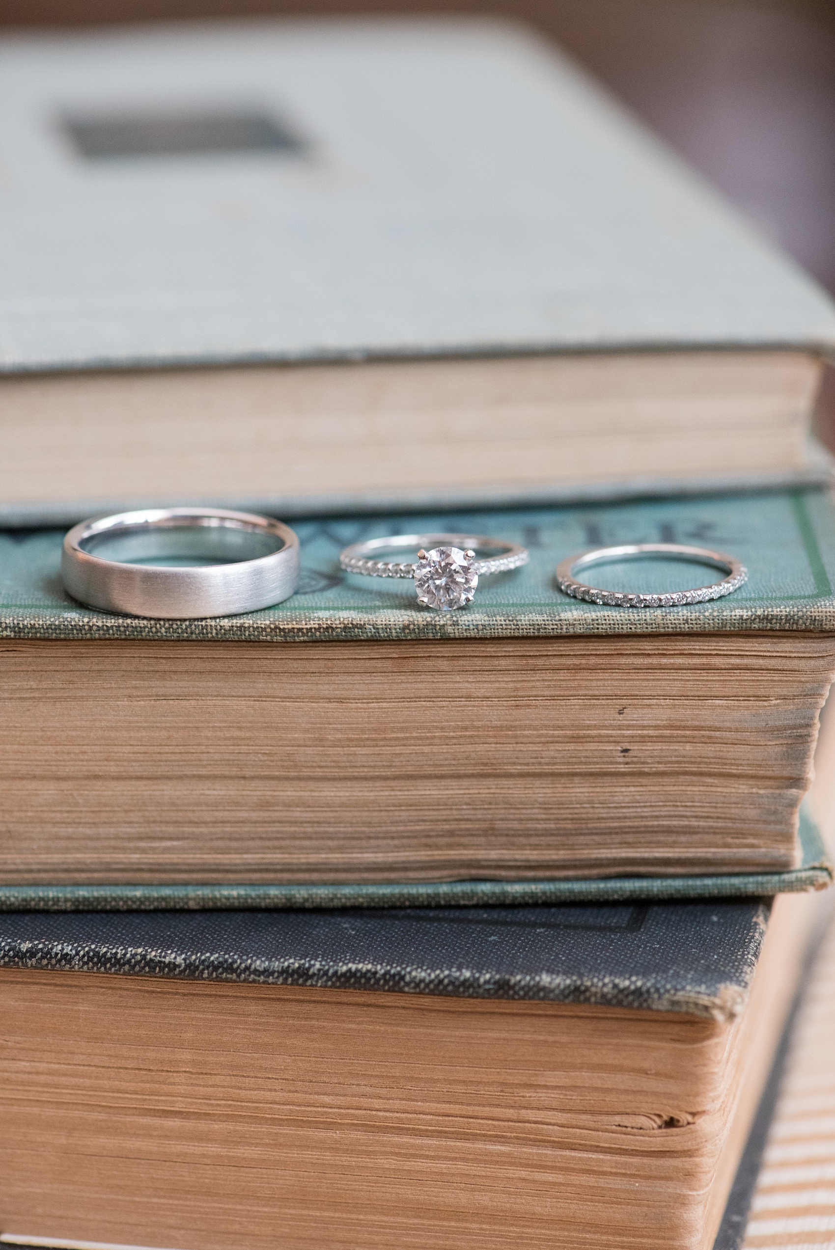 The Sutherland Wedding Photos by Mikkel Paige Photography. A detail picture of the bride and groom's white gold wedding rings on top of vintage books.