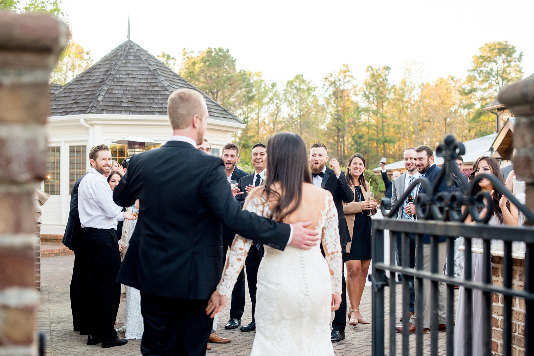 The Sutherland Wedding Photos by Mikkel Paige Photography. The bride and groom walk into their outdoor patio cocktail hour.