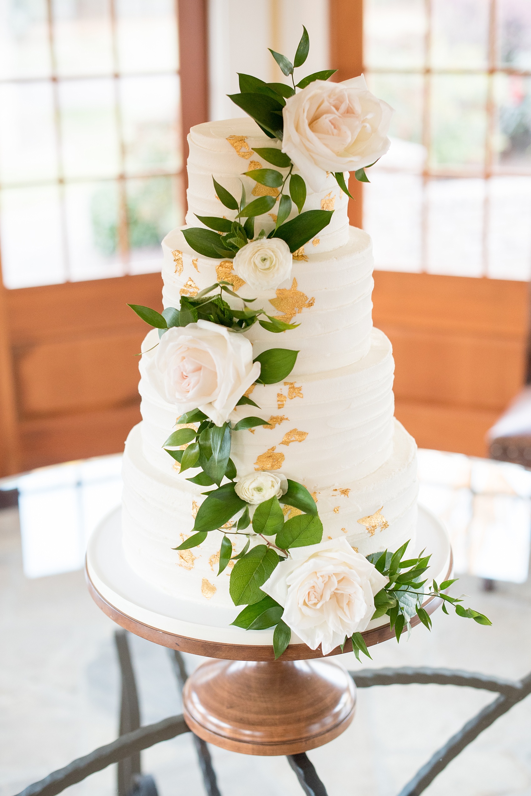The Sutherland Wedding Photos by Mikkel Paige Photography. White tiered buttercream cake with gold leaf and cascading white roses and greenery by Ashley Cakes NC. Planning by A Southern Soiree.