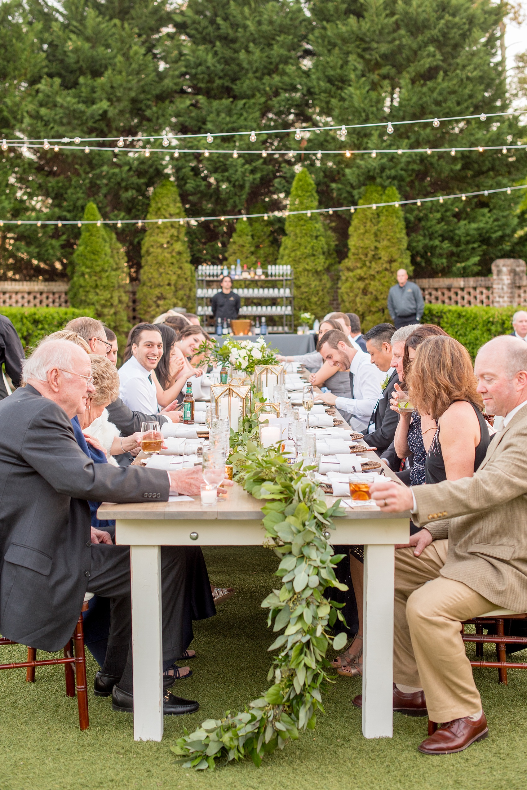 The Sutherland Wedding Photos by Mikkel Paige Photography. Guests enjoy dinner at farm tables by Cottage Luxe with eucalyptus garland.