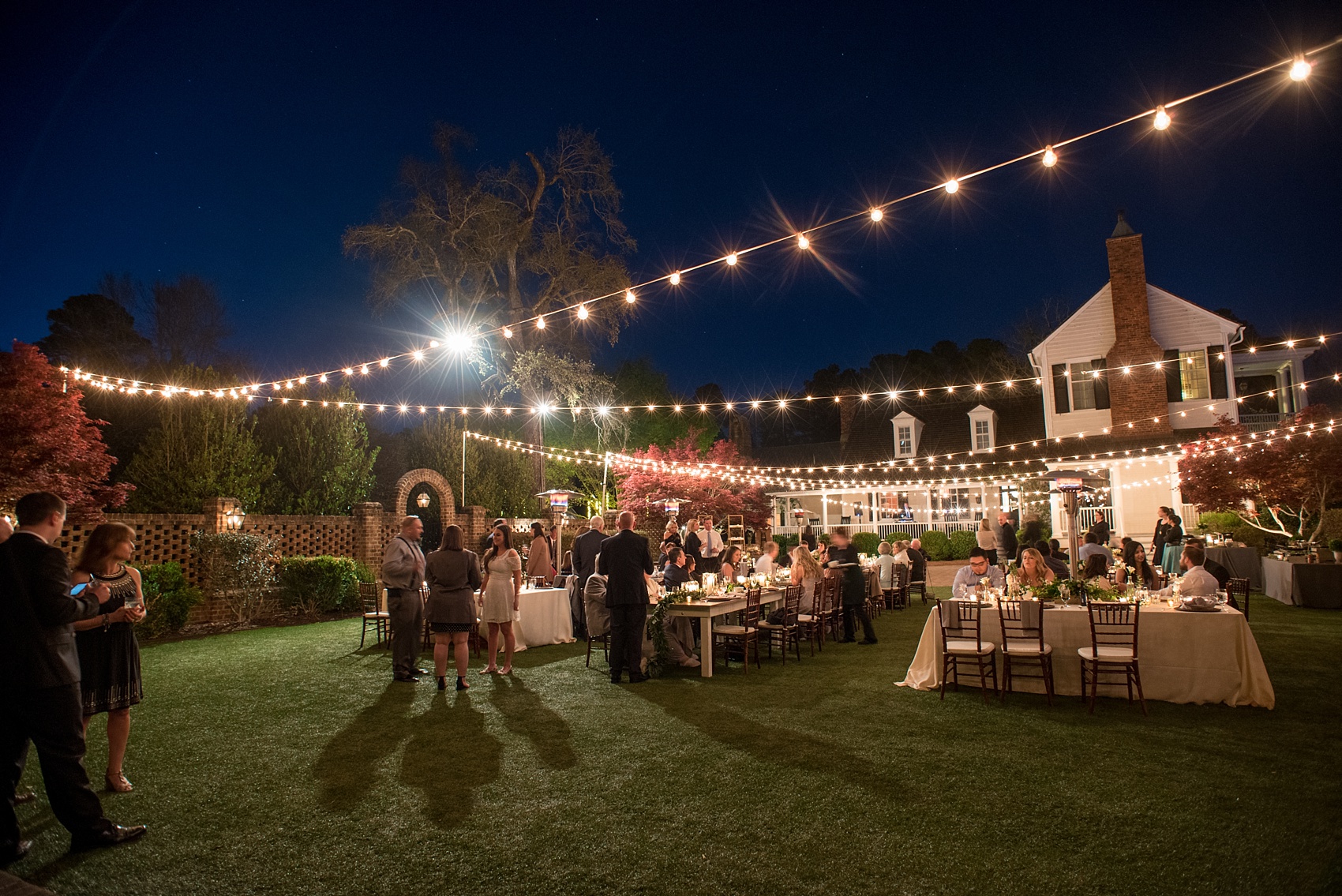 The Sutherland Wedding Photos by Mikkel Paige Photography. Night picture of the reception space with farm tables and market lights.