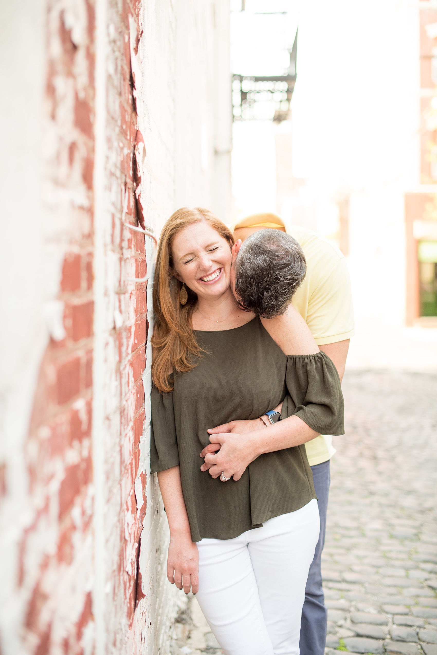 Spring Hoboken Engagement Photos by Mikkel Paige Photography. Picture of the couple laughing near a paint-peel urban wall.