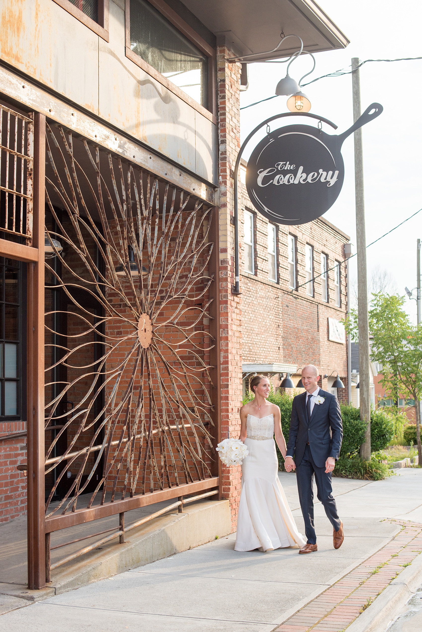 The Cookery Durham wedding photos by Mikkel Paige Photography. The bride and groom walk in front of a rustic iron gate.