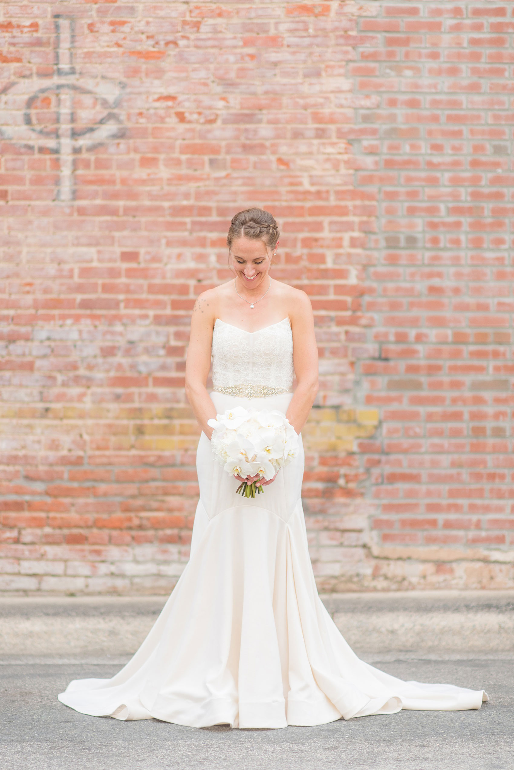 The Cookery Durham wedding photos by Mikkel Paige Photography. Picture of the bride in her strapless wedding gown and white orchid bouquet against an urban, vintage painted wall.