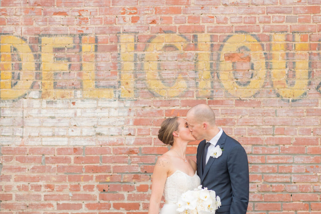 The Cookery Durham wedding photos by Mikkel Paige Photography. Picture of the bride and groom against an urban, vintage painted wall. Planning by Erin McLean Events and flowers by Tre Bella.