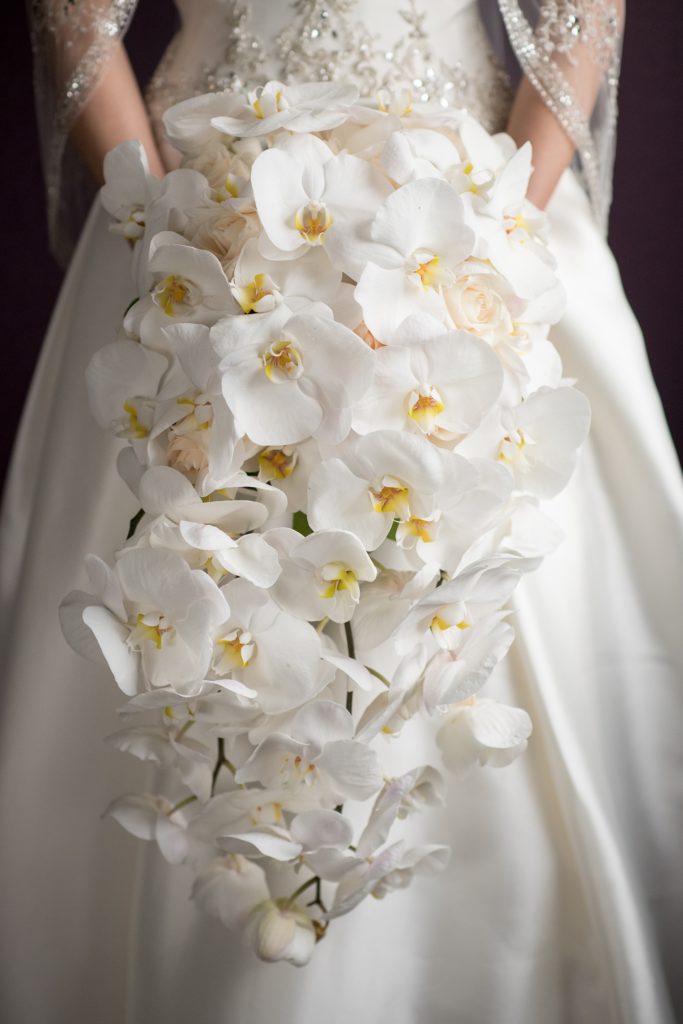 Mikkel Paige Photography wedding photos at The Fox Hollow, Long Island. Picture of the bride and groom holding hands with her all white cascading orchid bouquet.