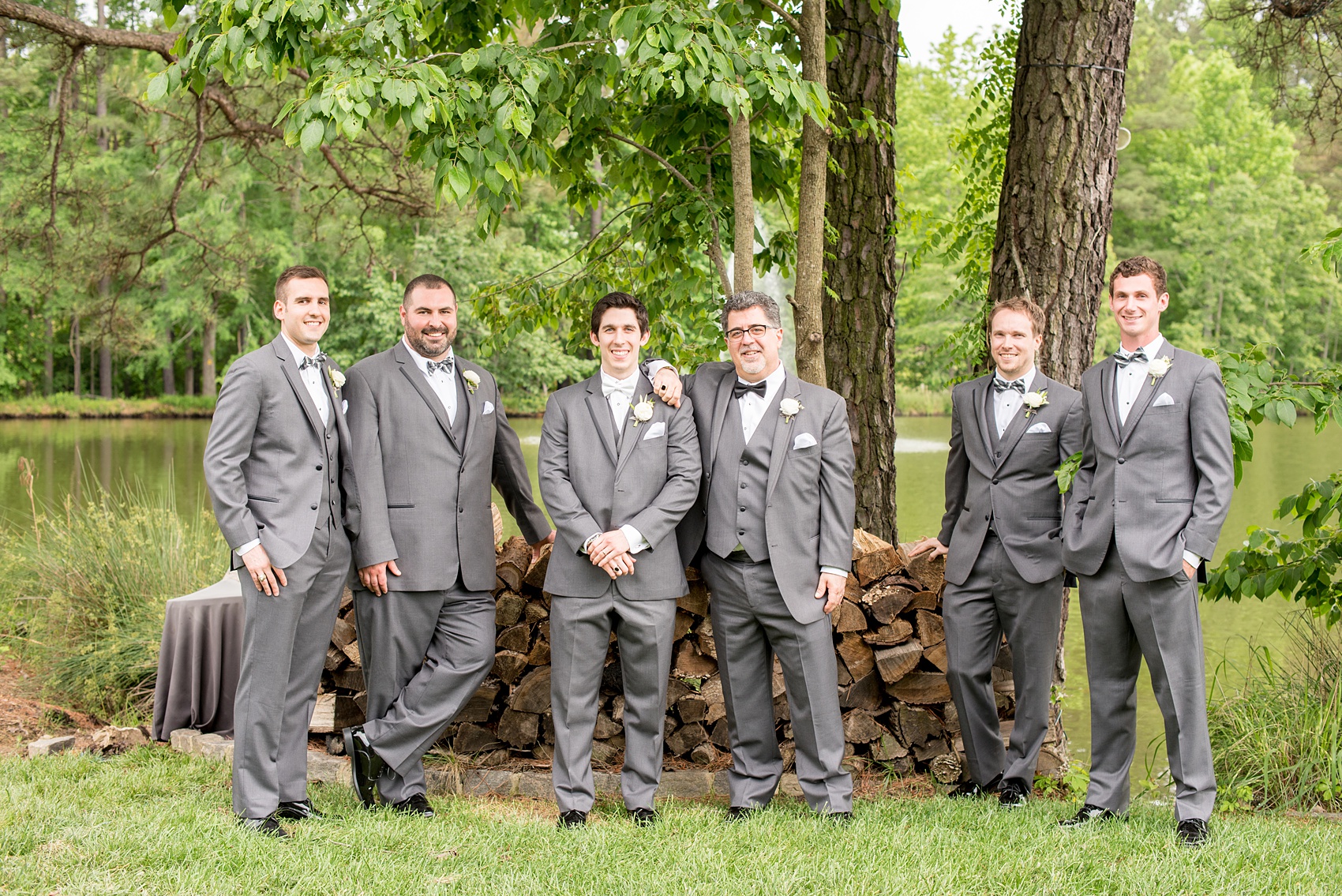 Pavilion at Angus Barn wedding photos by Mikkel Paige Photography. Relaxed candid like groomsmen photo of them in grey tuxedos and ranunculus boutonnieres with hints of Lily of the Valley by Meristem Floral. 