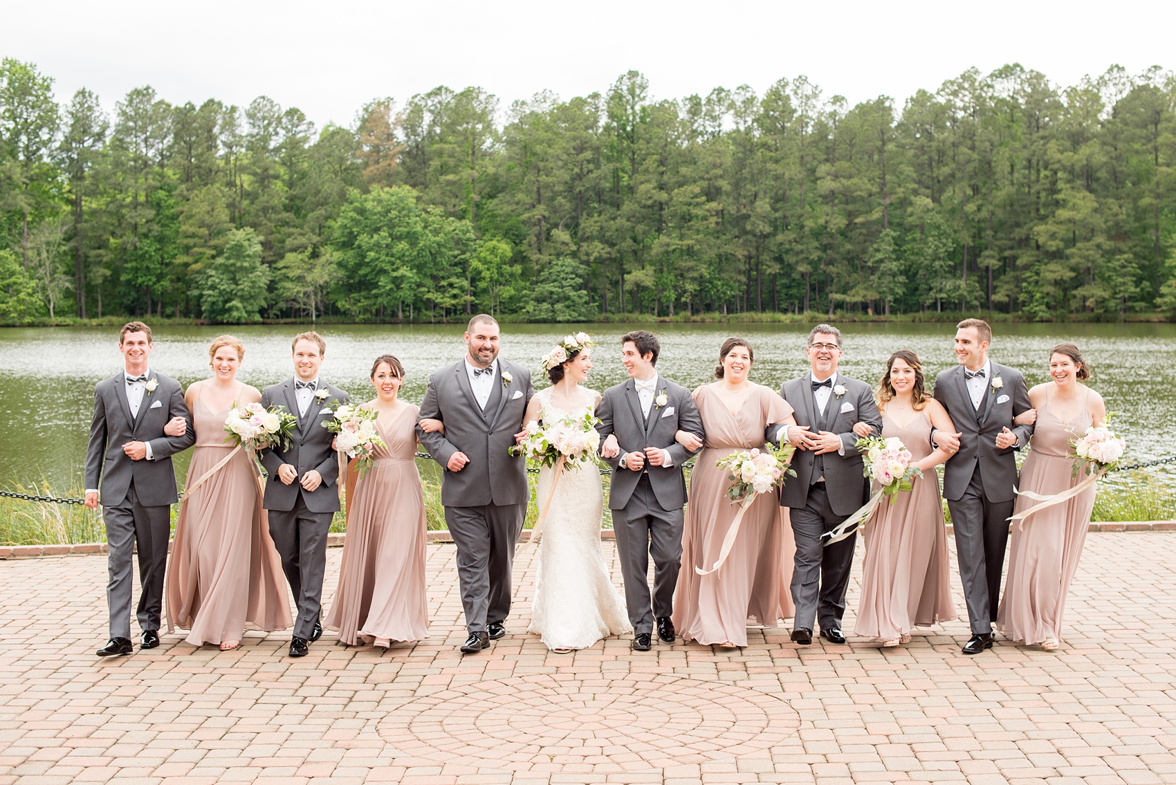 Pavilion at Angus Barn wedding photos by Mikkel Paige Photography. Creative picture of the bridal party walking towards the camera with the bridesmaids in dusty rose mismatched chiffon Jenny Yoo gowns and the groomsmen in grey suits.