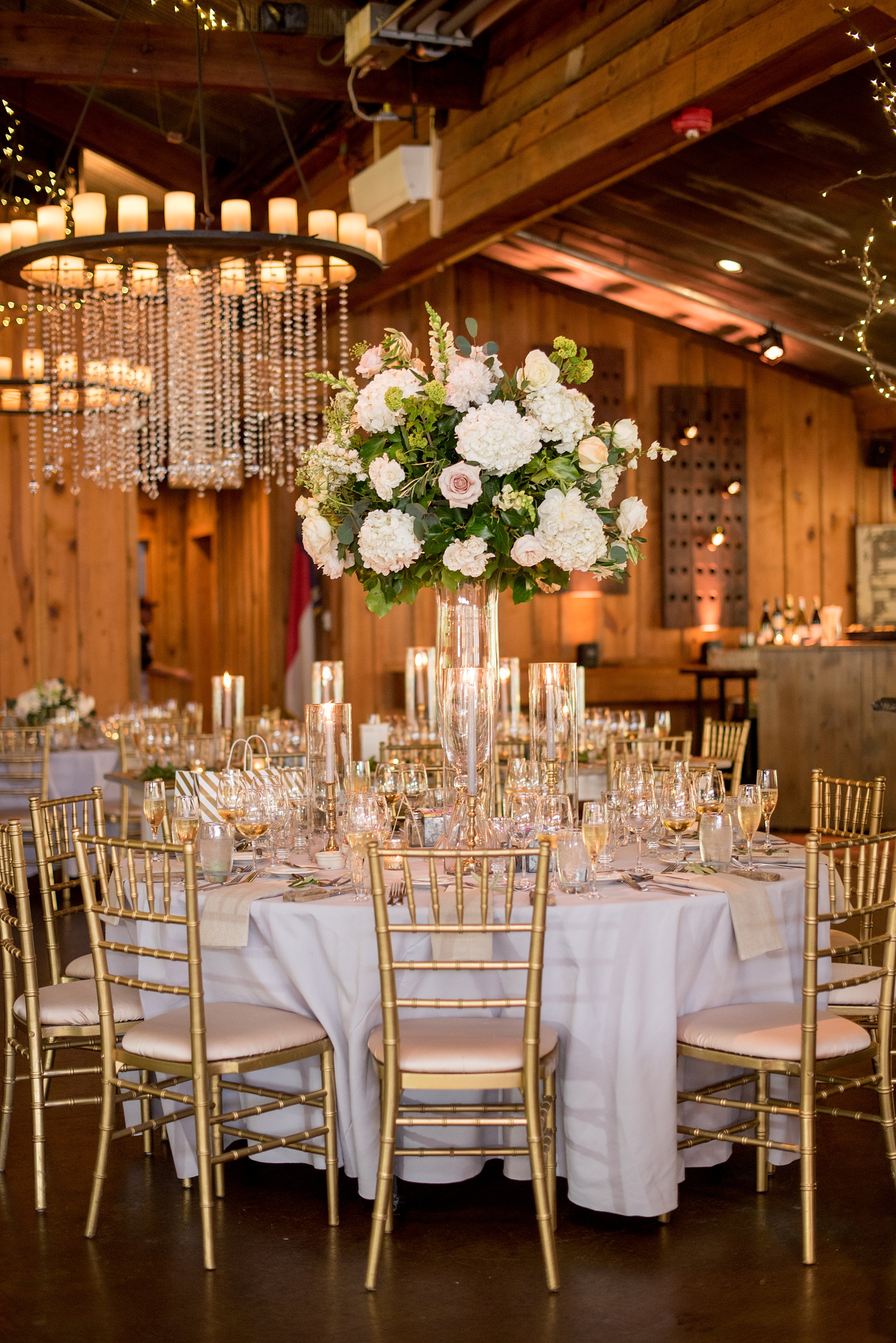 Pavilion at Angus Barn wedding photos by Mikkel Paige Photography. Picture of the round tables from drenched in candlelight and high floral centerpieces from Meristem Floral.