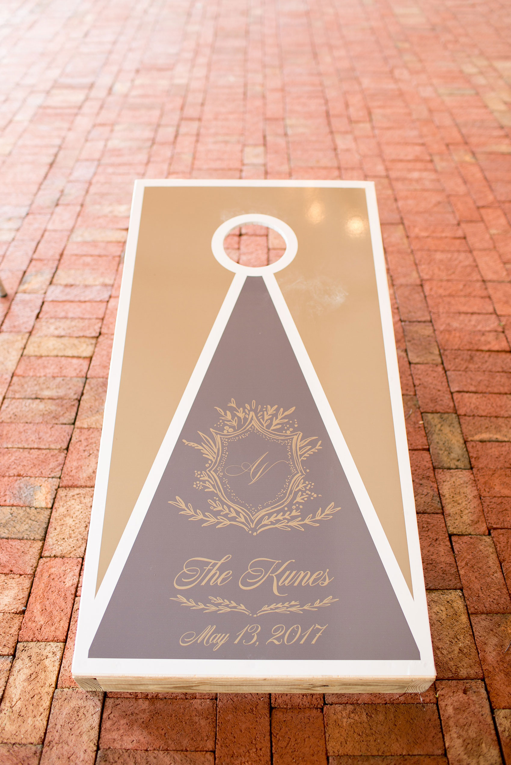 Pavilion at Angus Barn wedding photos by Mikkel Paige Photography. Picture of the grey and gold custom corn hole game complete with laurel garland motif.