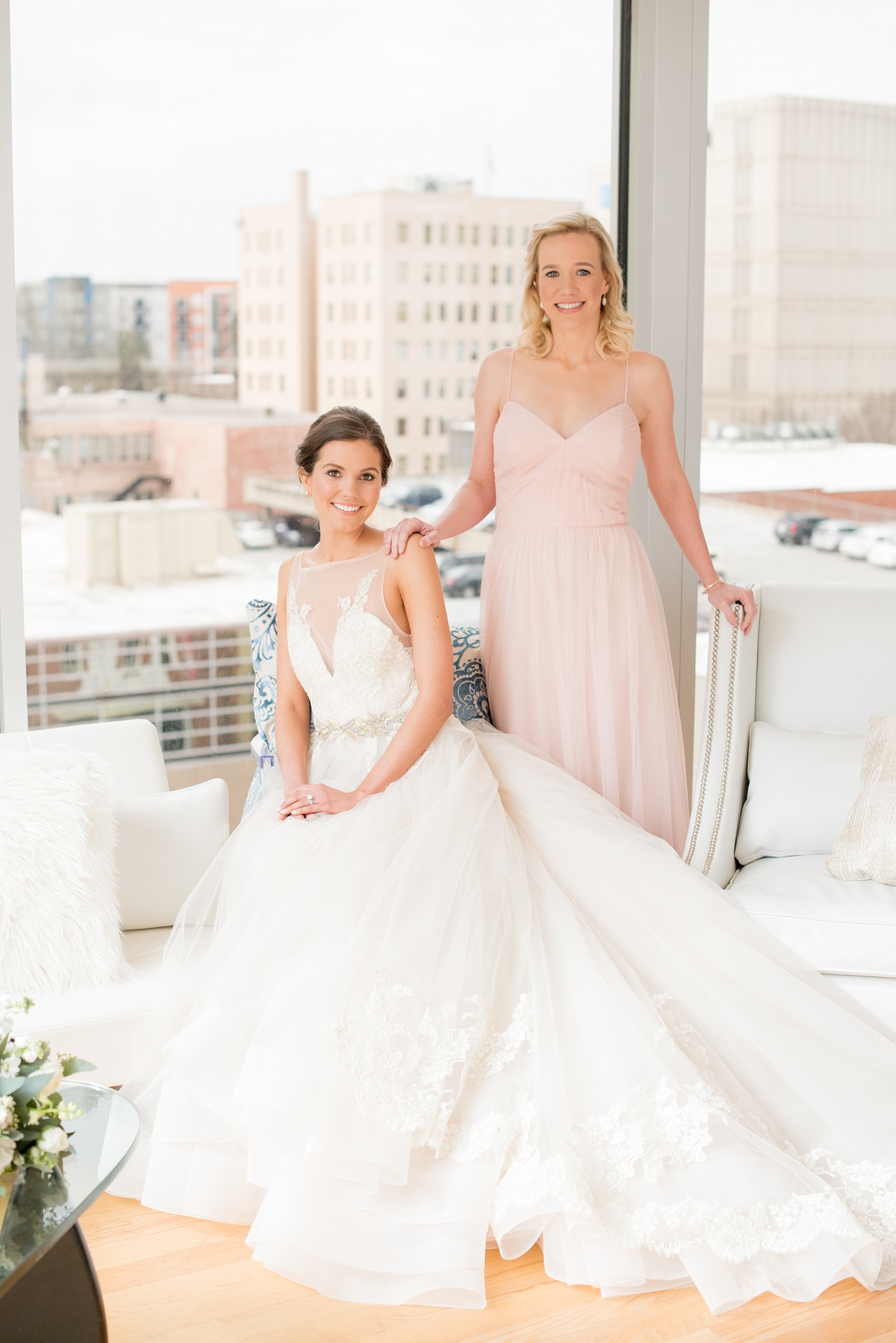 The Glass Box Raleigh wedding photos by Mikkel Paige Photography. Picture of the bride in a Lazaro gown in this modern downtown venue. The bridesmaid wore a pink Hayley Paige occasion gown.